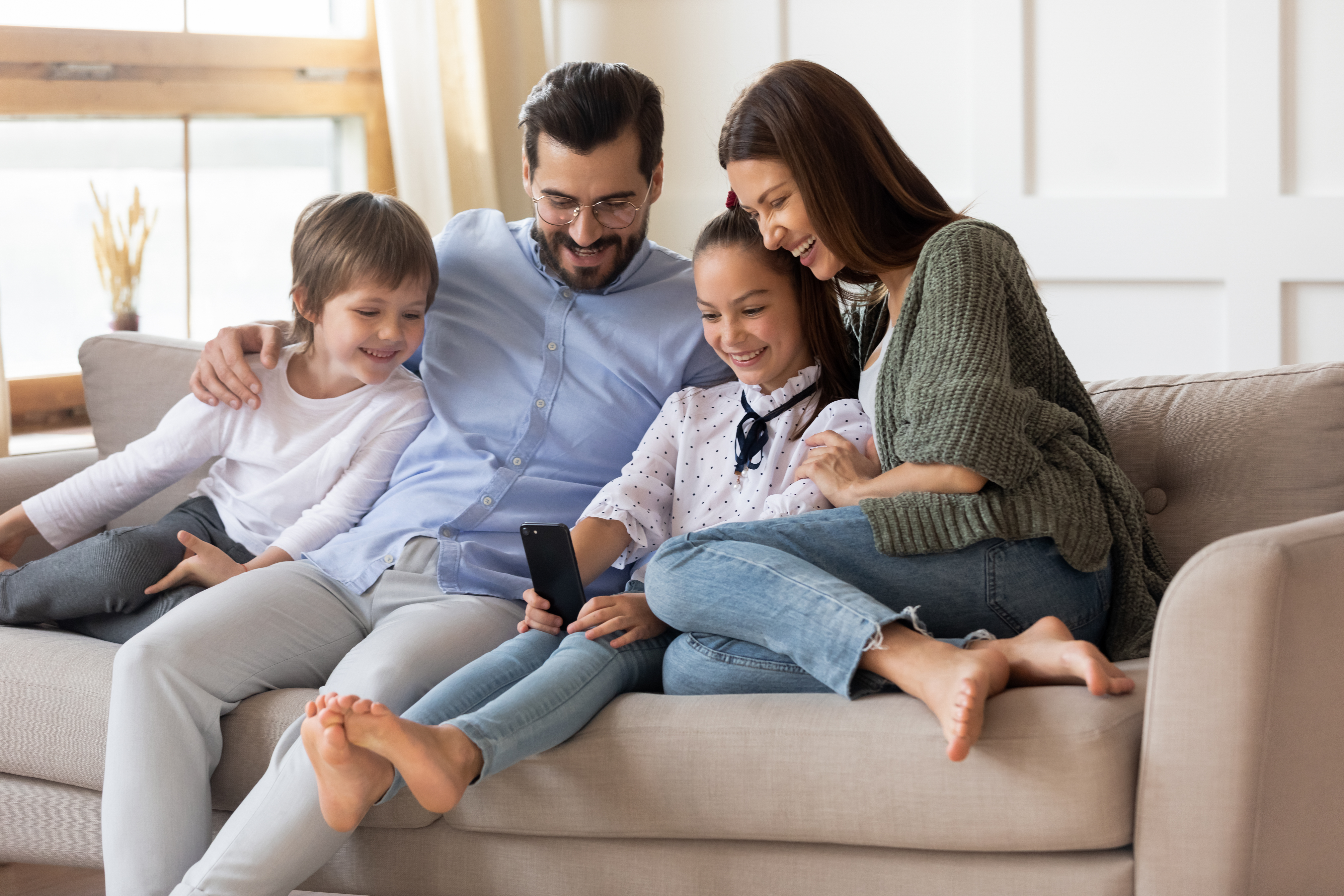 Happy parents relaxing at home with their young children | Source: Shutterstock