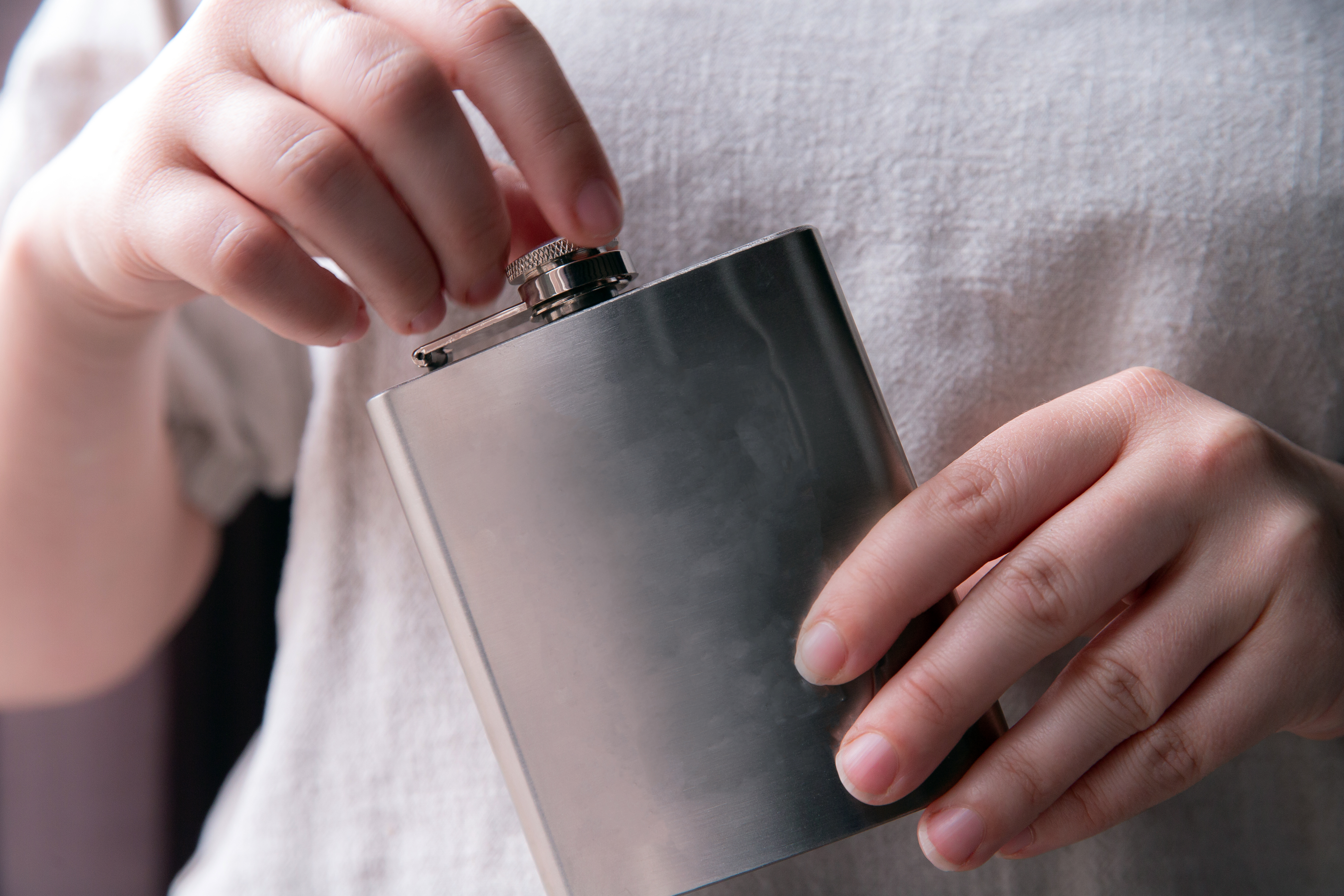 Hand holding a stainless steel hip flask | Source: Shutterstock