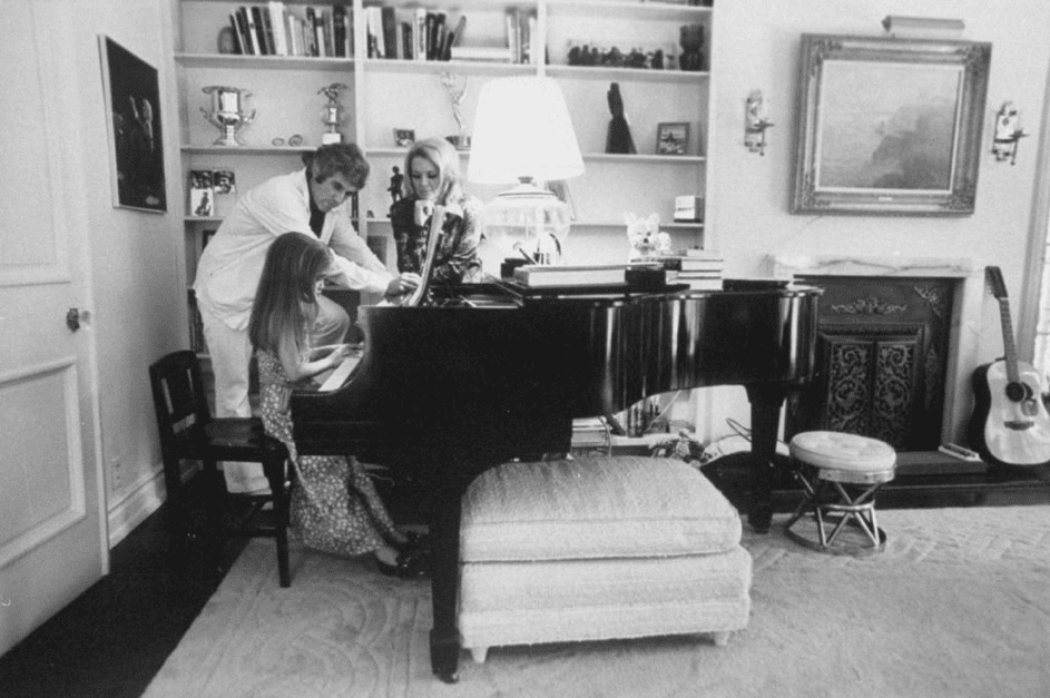 Burt Bacharach und seine Frau Angie Dickinson schauen zu, wie Nikki Klavier spielt. Mai 1974. | Quelle: Getty Images