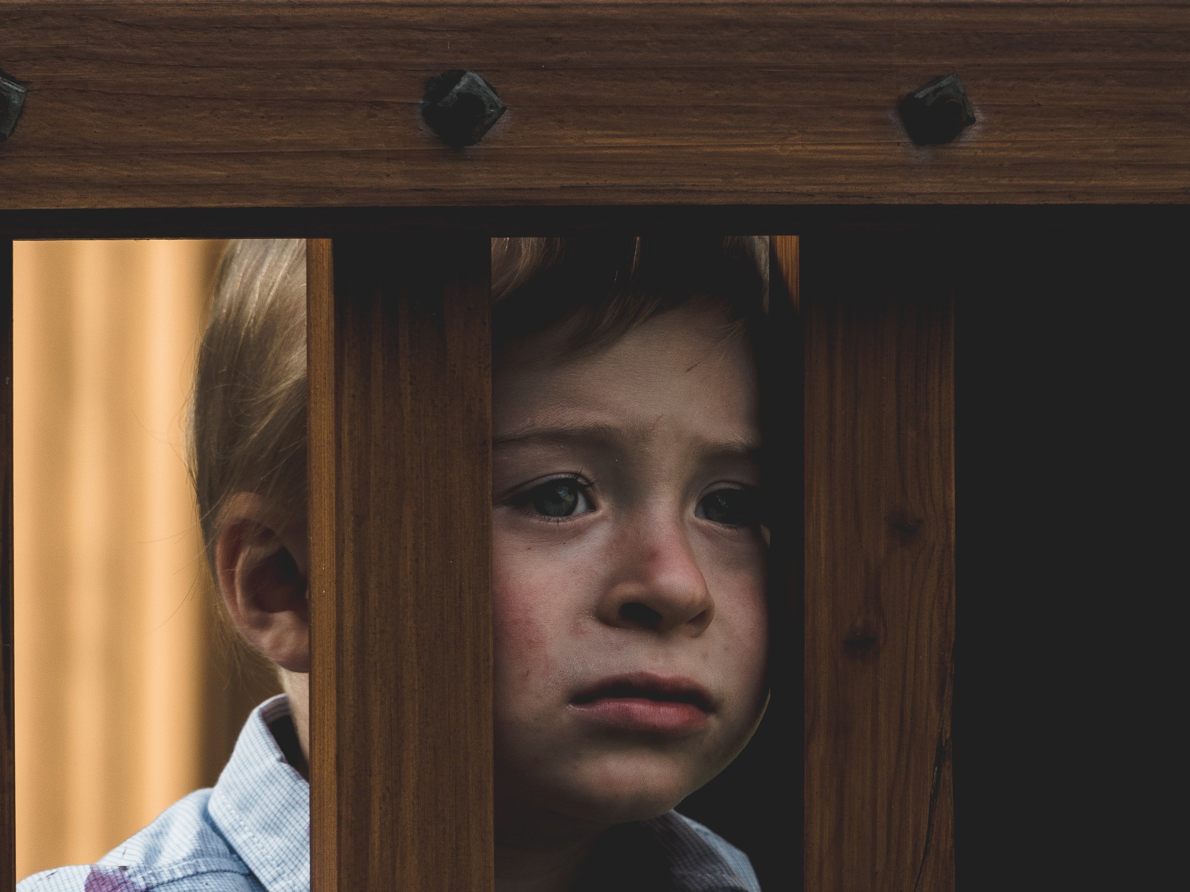Boy leaning on a wooden railing. | Source: Unsplash