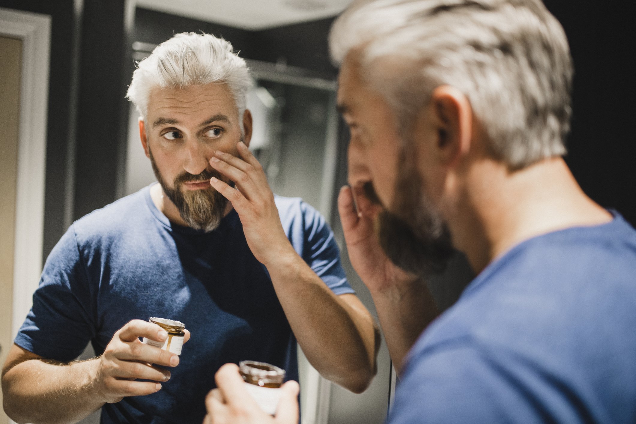 Un homme d'âge moyen applique une crème hydratante sur son visage. | Photo : Getty Images