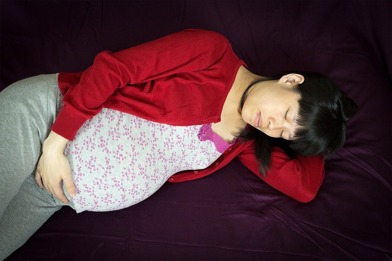 Mujer embarazada recostada sobre una cama. | Foto: Needpix.com