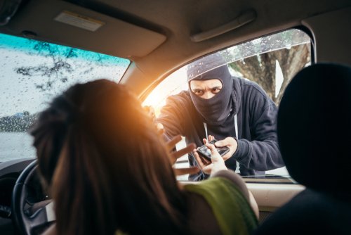 Hombre asaltando a una mujer dentro de su auto. | Foto: Shutterstock