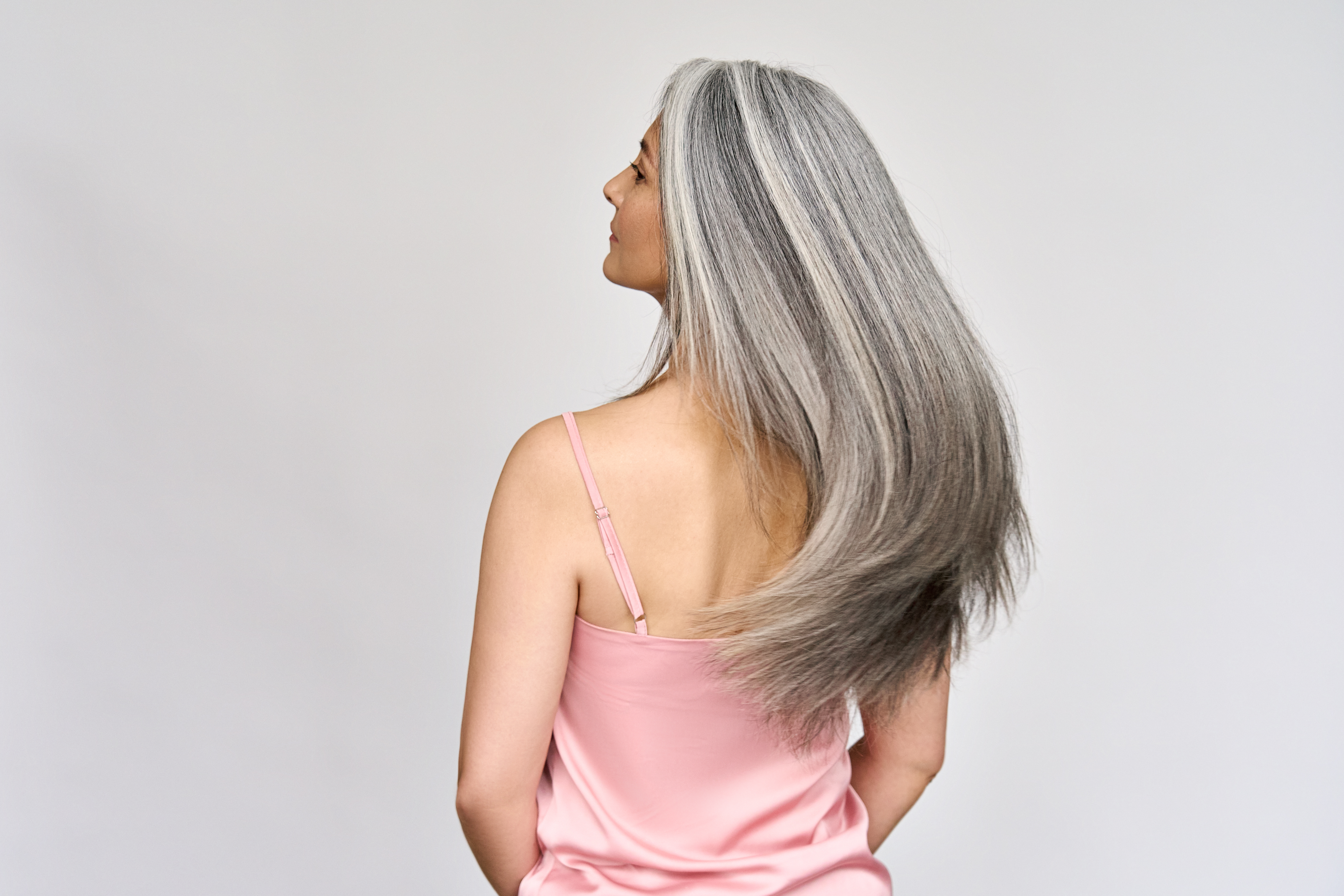 Grey-haired woman swinging her hair | Source: Shutterstock