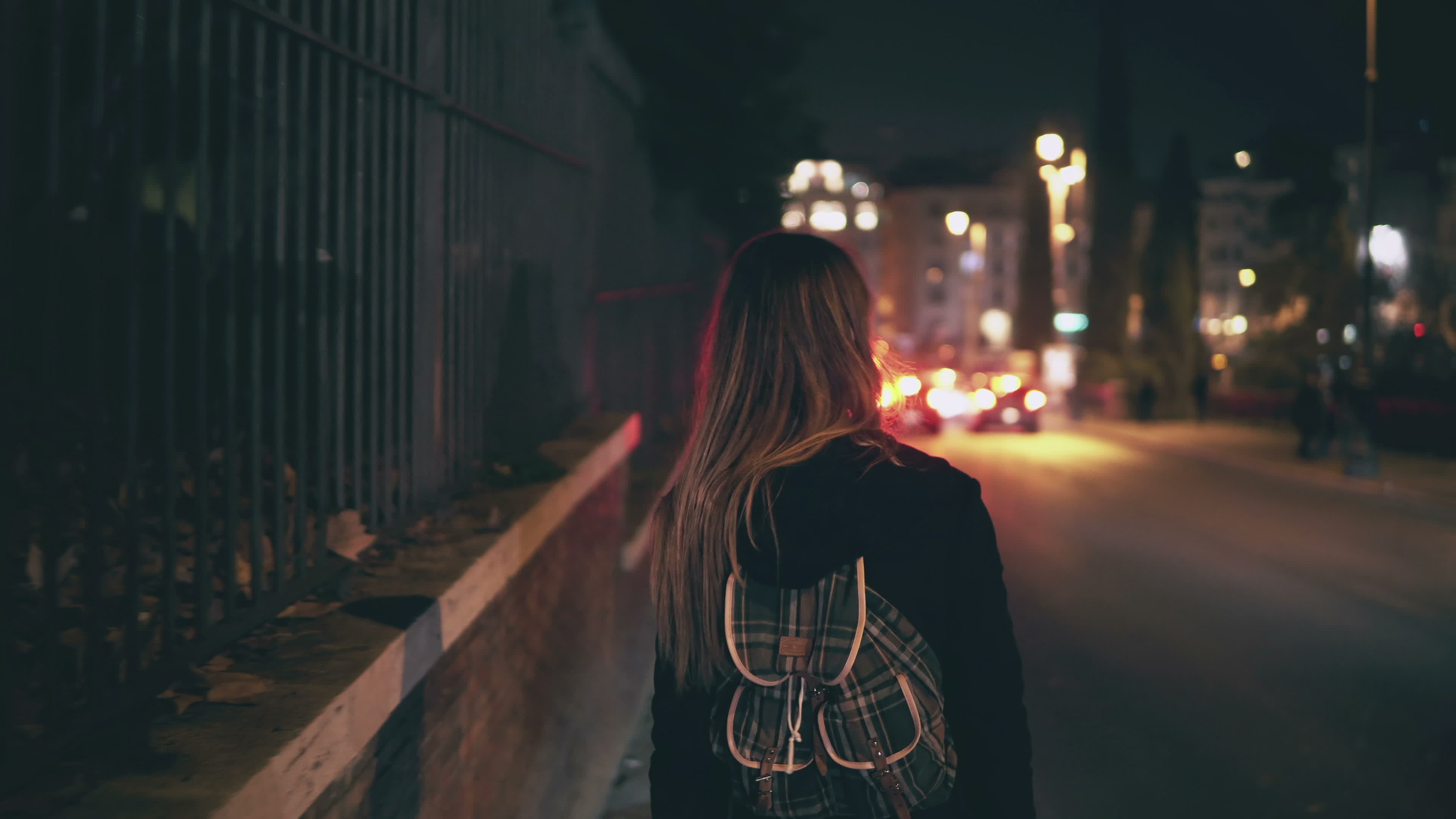 Girl with bag is walking through the night city | Source: Shutterstock.com
