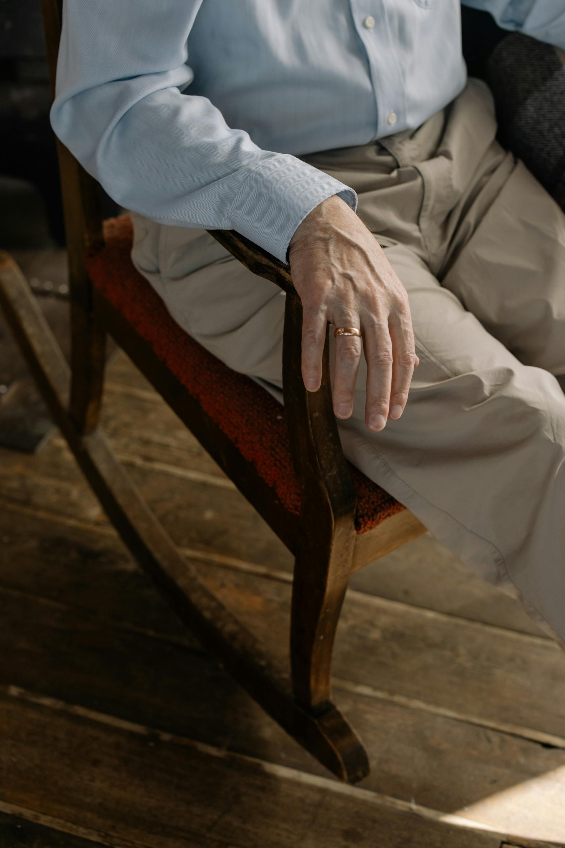 A close-up shot of a man sitting in an armchair wearing a wedding ring | Source: Pexels