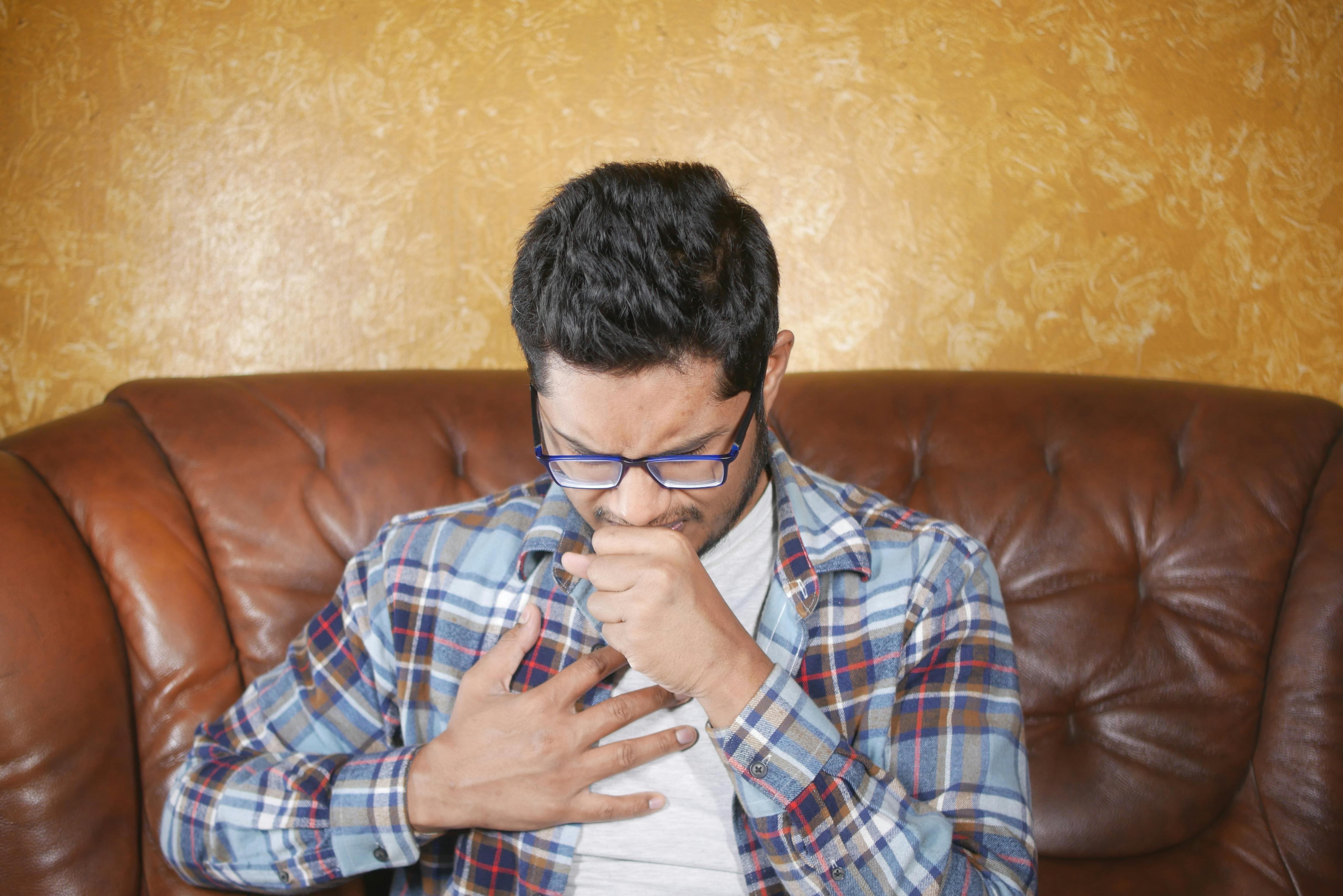 A man holding his chest as he coughs into his hand | Source: Pexels