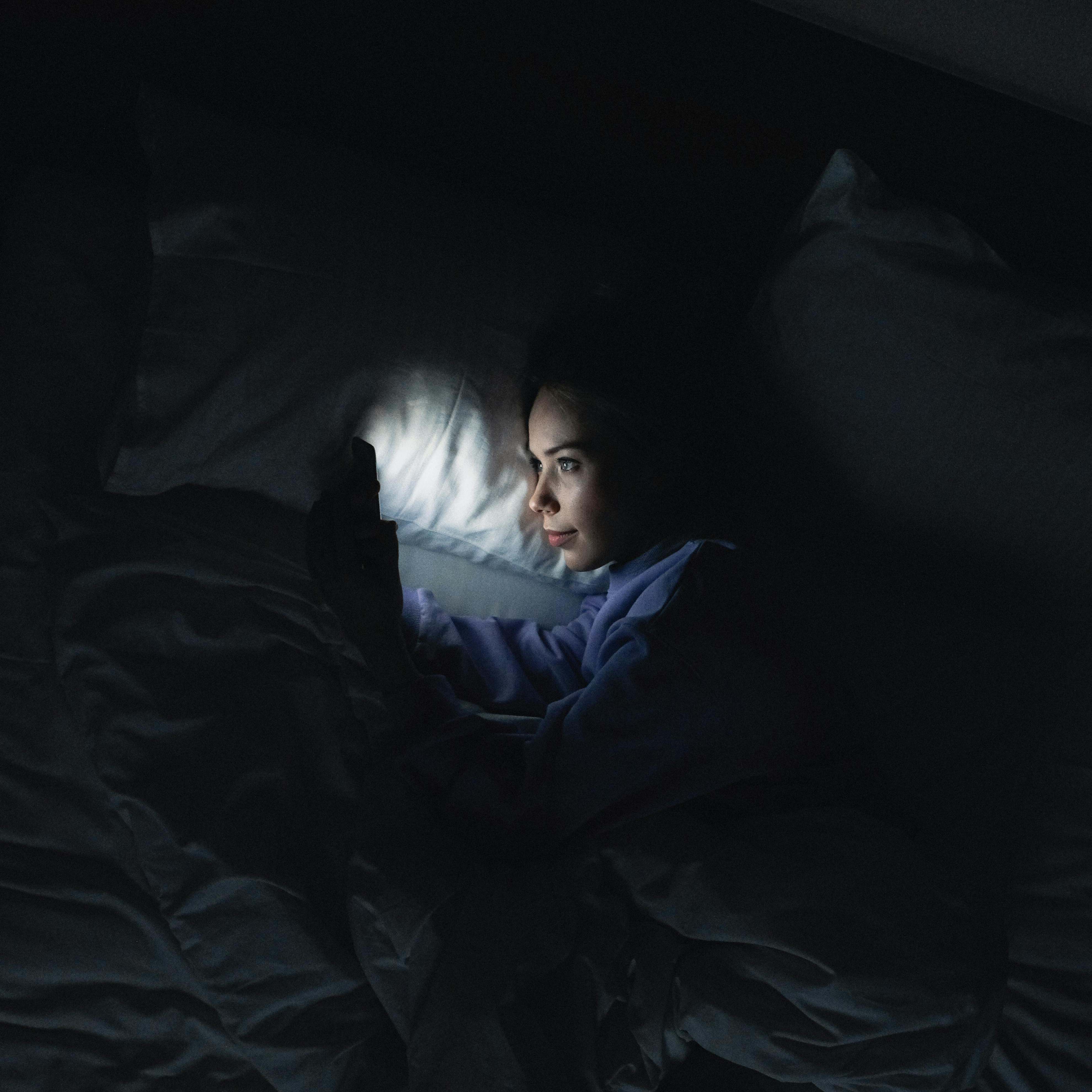 A woman in bed responding to a phone call | Source: Pexels