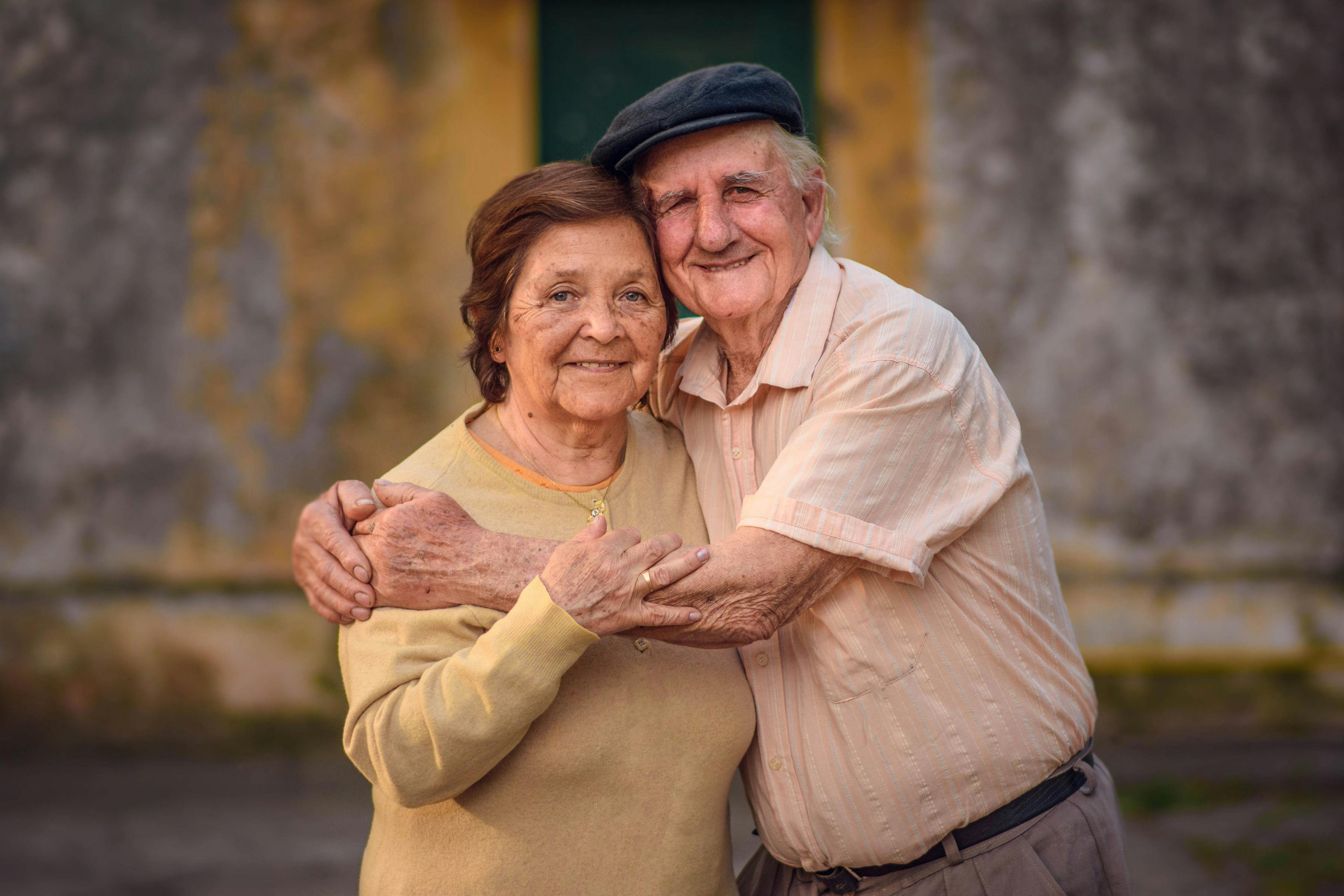 An older couple embraces while posing outdoors. | Source: Pexels