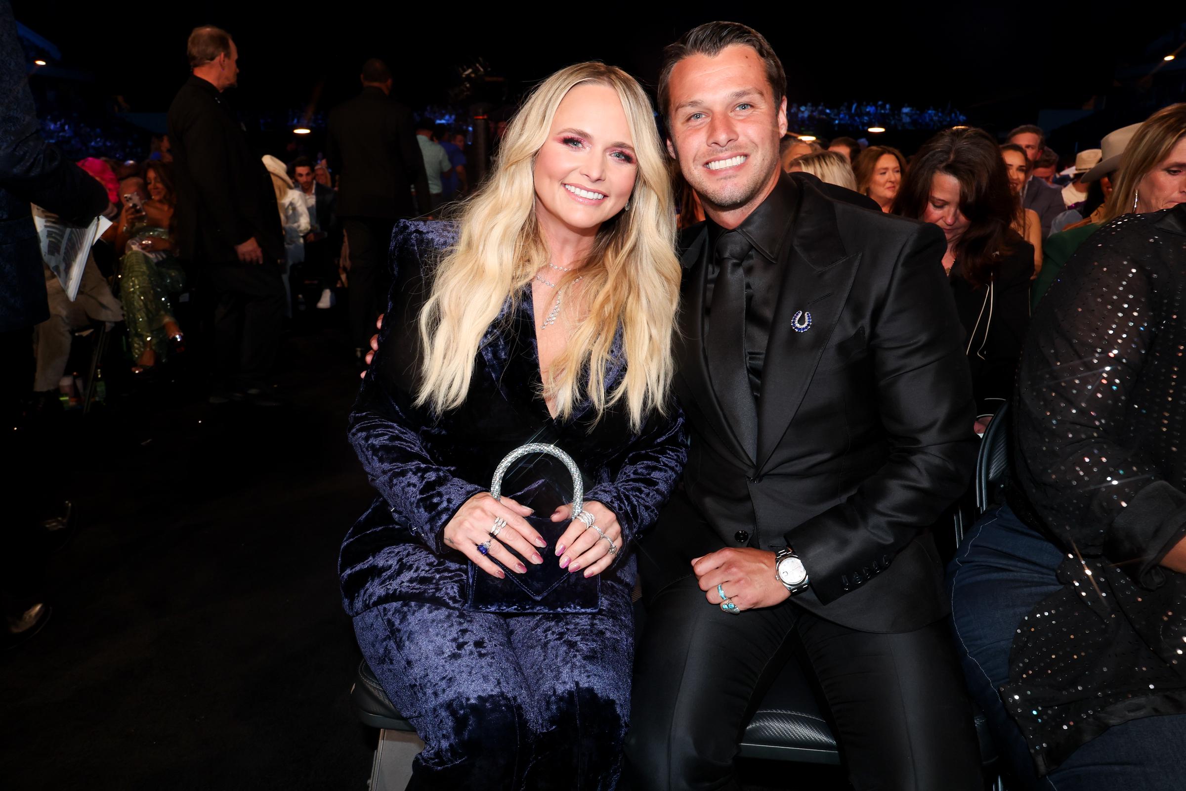 Miranda Lambert and Brendan McLoughlin attend the 60th ACM Awards at The Star in Frisco. The couple sits side by side, with Lambert glowing in a velvet look and McLoughlin in an all-black suit, both beaming for the camera.