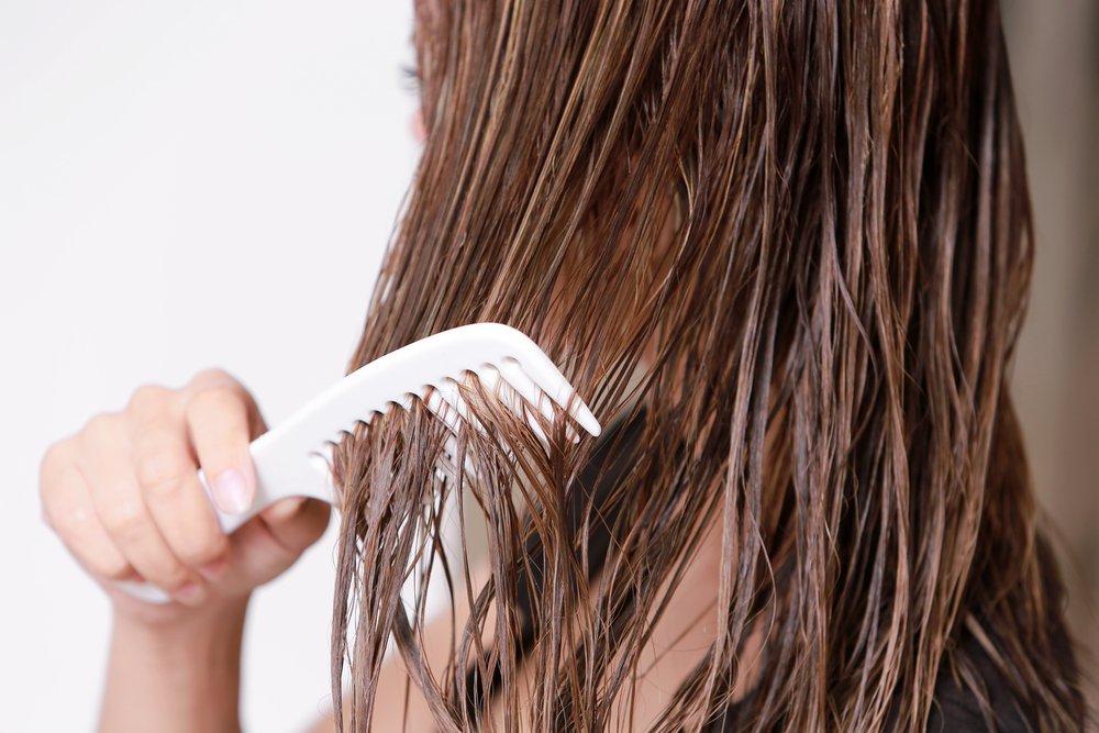 Mujer peinándose el cabello mojado. | Foto: Shutterstock