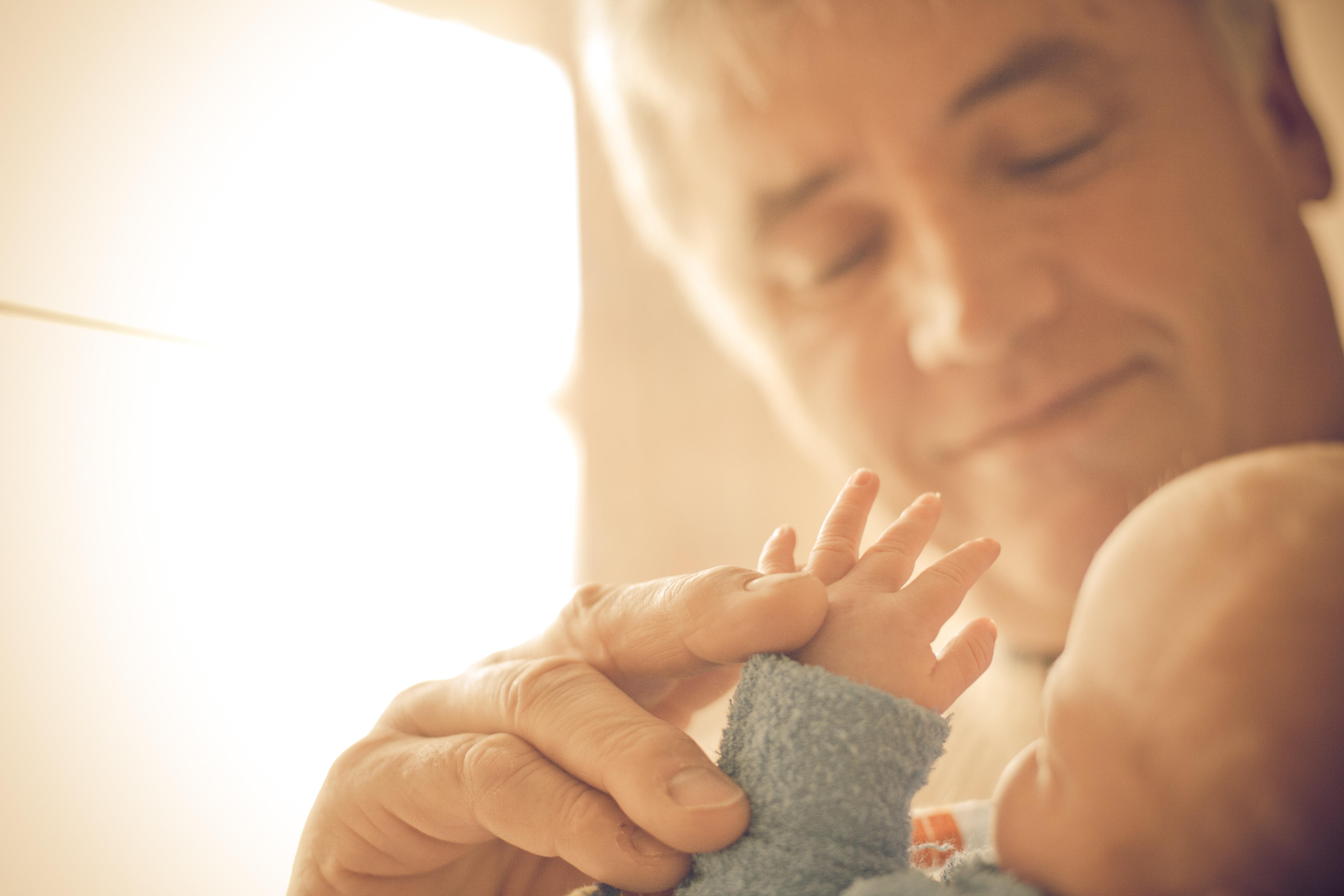 Ein älterer Mann hält die Hand seines Enkelkindes und schätzt die Verbindung zwischen ihnen. | Quelle: Getty Images