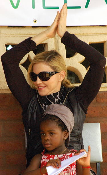 US artist Madonna and her adopted daughter Mercy James sit at a community school funded by her during a visit to Gumulira Millenium villages in Mchinji, west of the capital, Lilongwe, on April 5, 2010 | Photo: Getty Images
