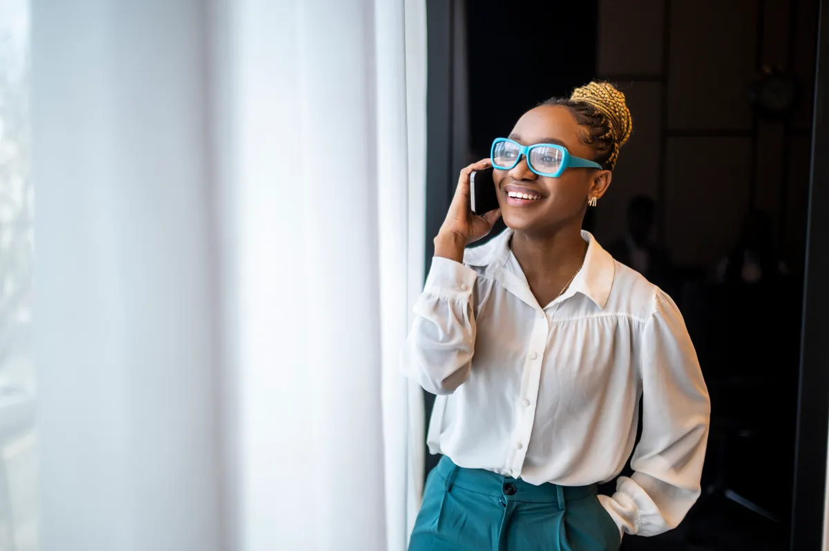 A smiling black female entrepreneur talking on the phone | Source: Getty Images