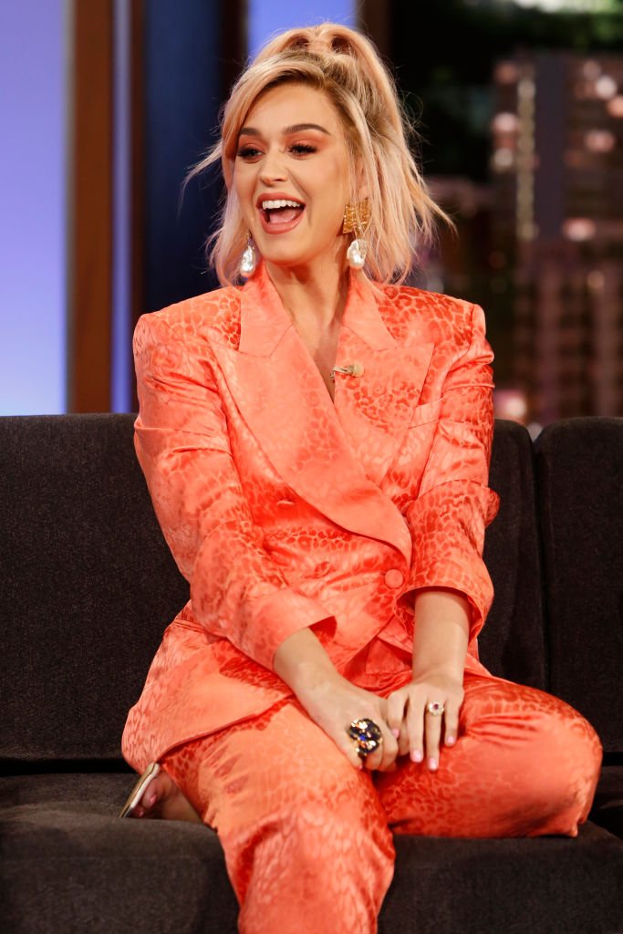 Katy Perry sits on a couch and laughs during her interview on "Jimmy Kimmel Live!" on February 12, 2020, | Source: Randy Holmes/ABC via Getty Images