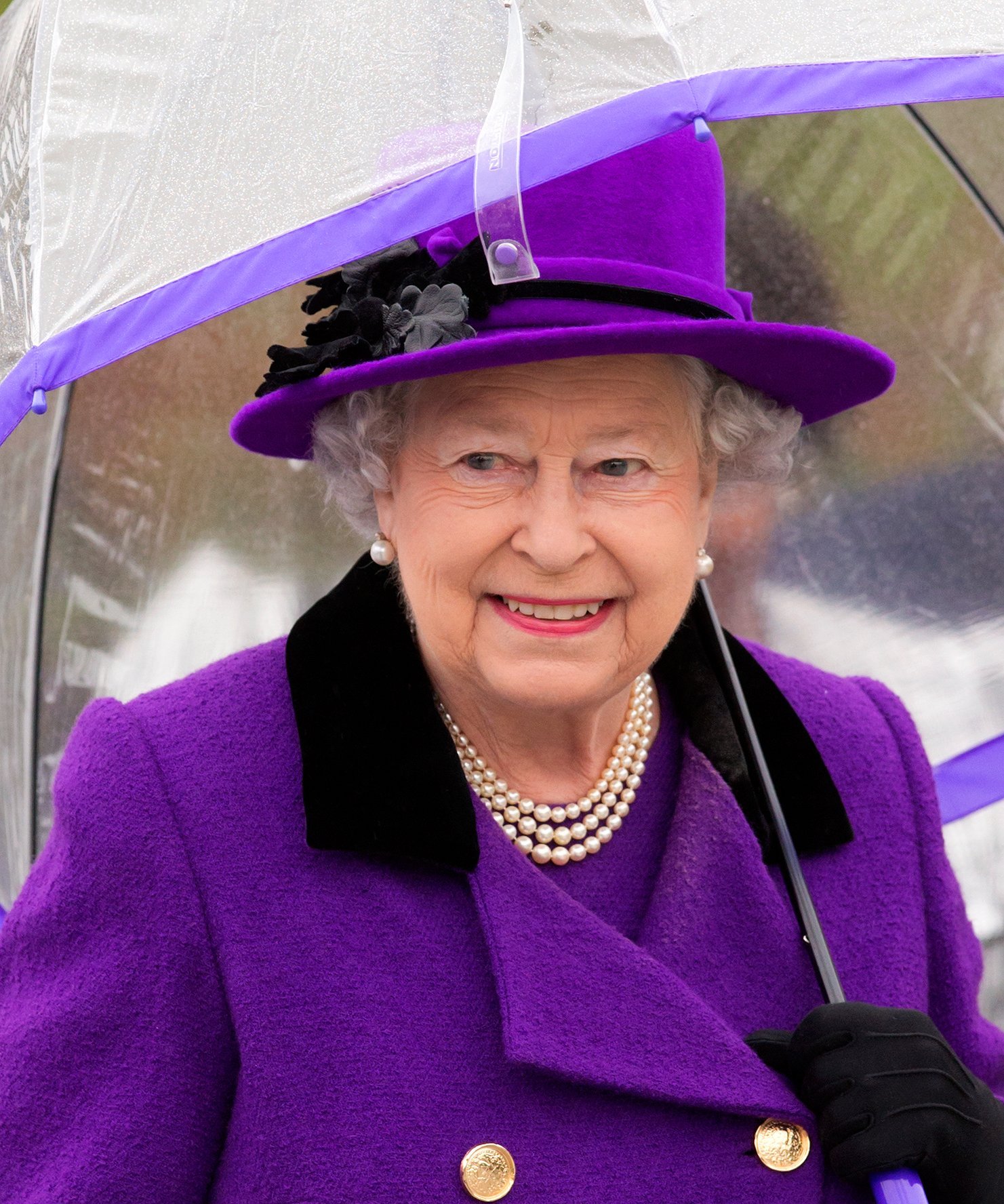 Queen Elizabeth II shelters under an umbrella as attends the opening of the newly developed Jubilee Gardens on October 25, 2012 | Photo: Getty Images