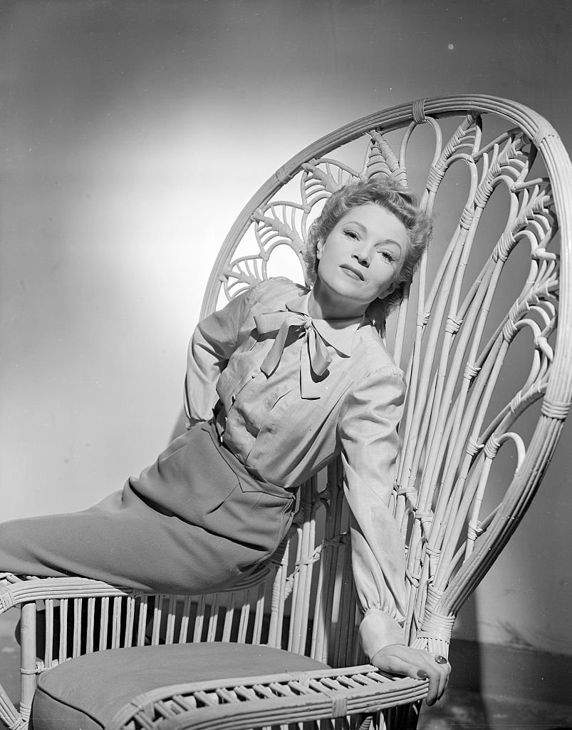L'actrice française Annabella (alias Suzanne Georgette Charpentier) appuyée contre une chaise en rotin à dossier haut; Tourné en 1944. | Photo : Getty Images