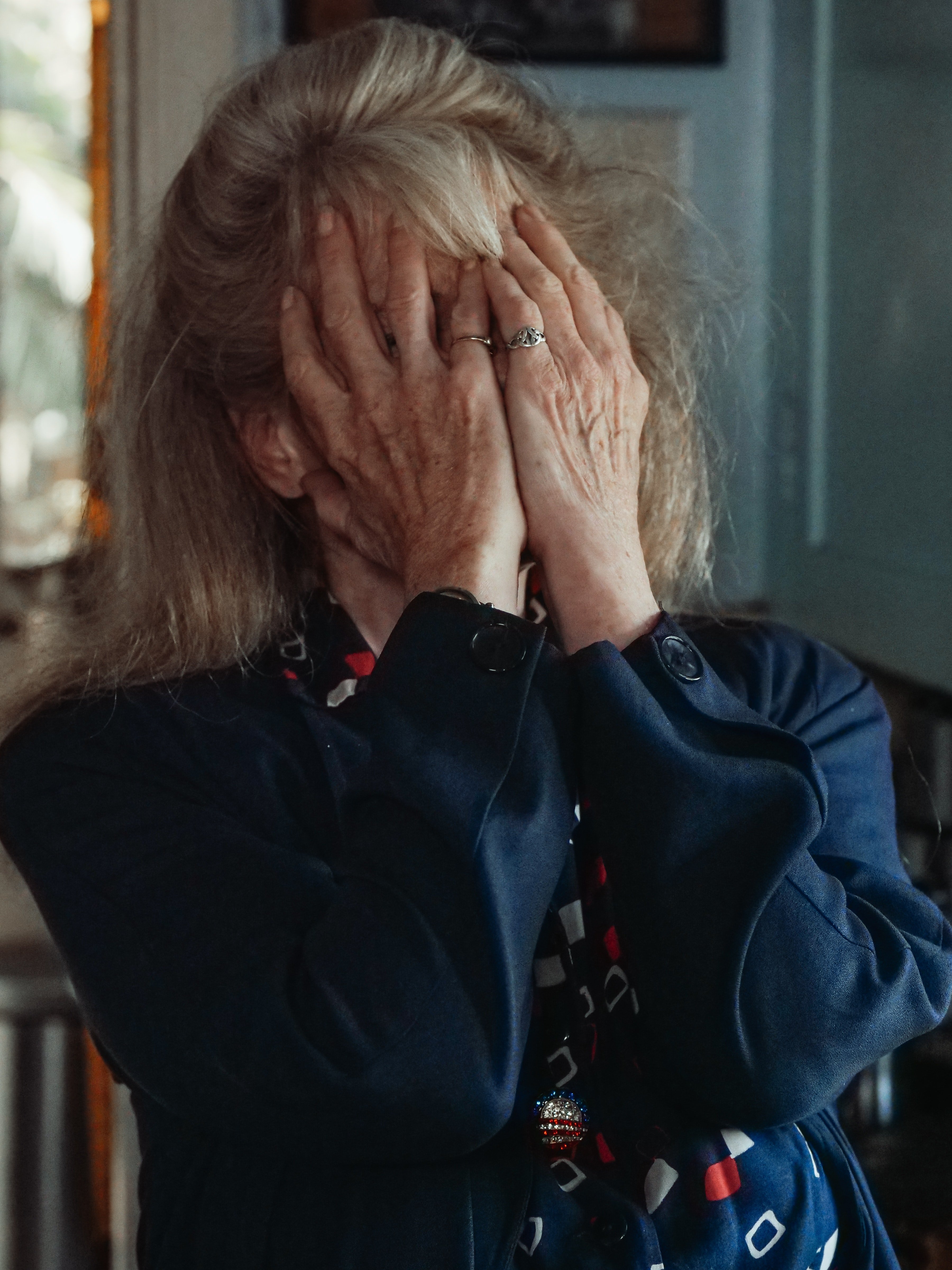 Mujer mayor tapando su cara con sus manos. | Foto: Pexels