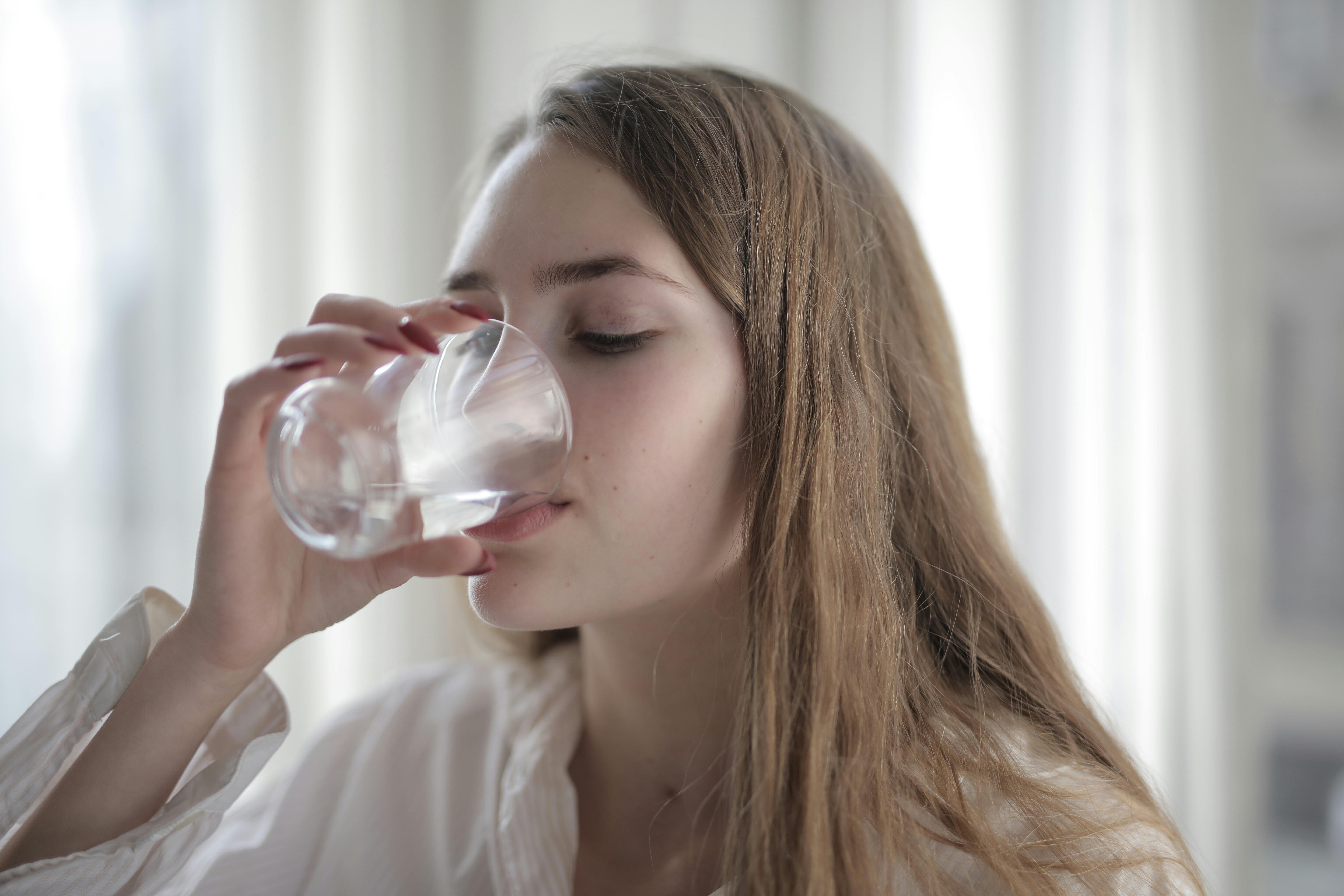 A woman drinking a glass of water. | Source: Pexels