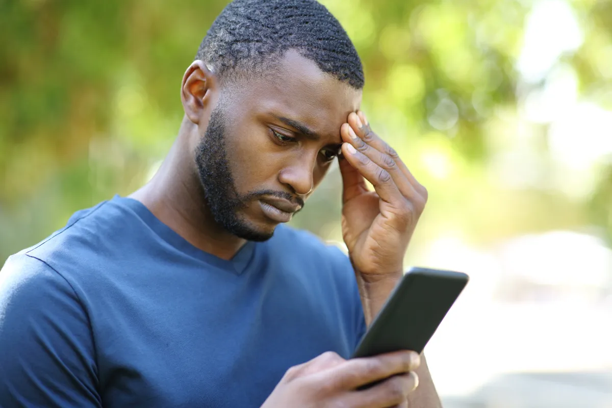 An anxious black man checking his smart phone in a park | Source: Getty Images