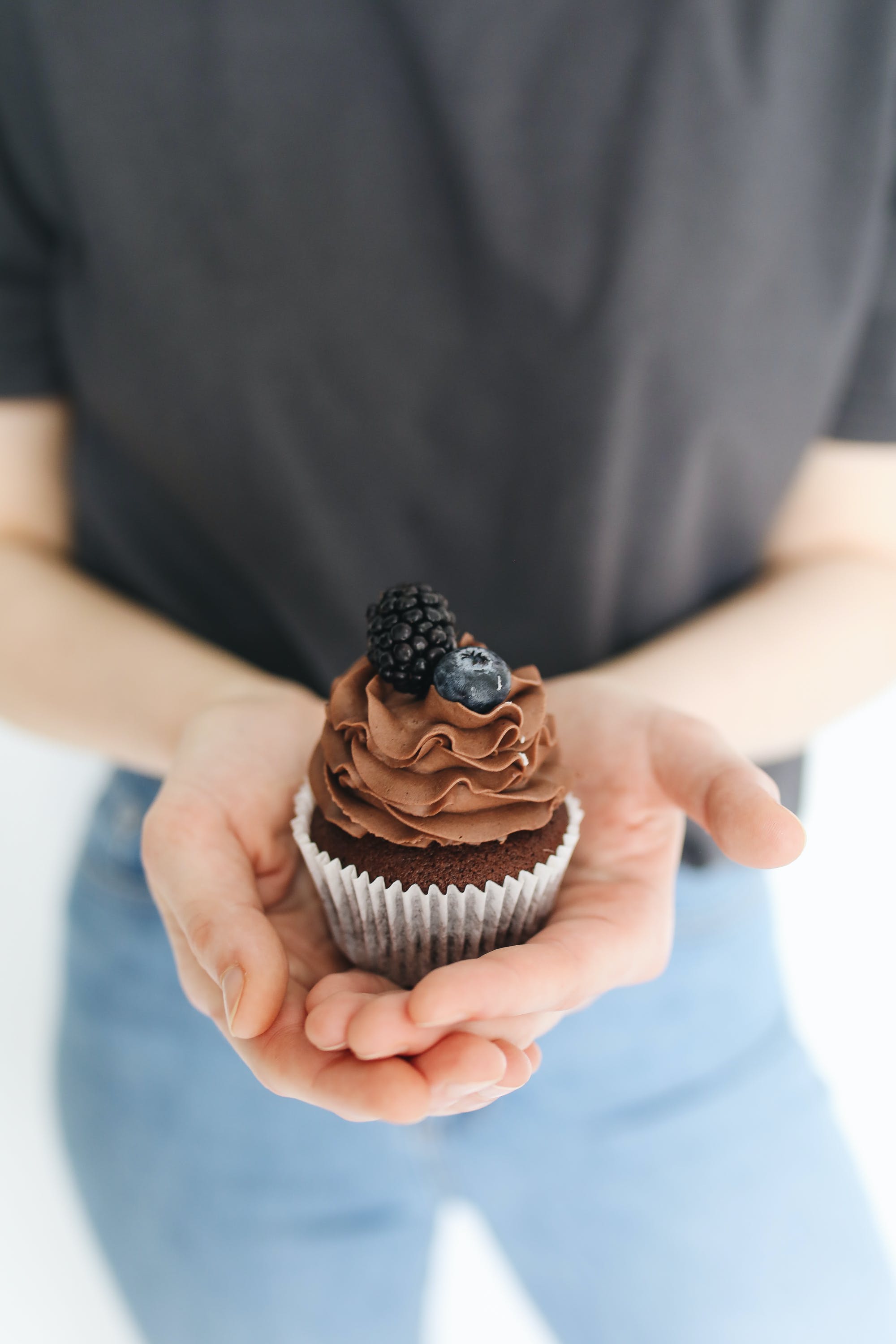 A person holding a chocolate cupcake. | Source: Pexels