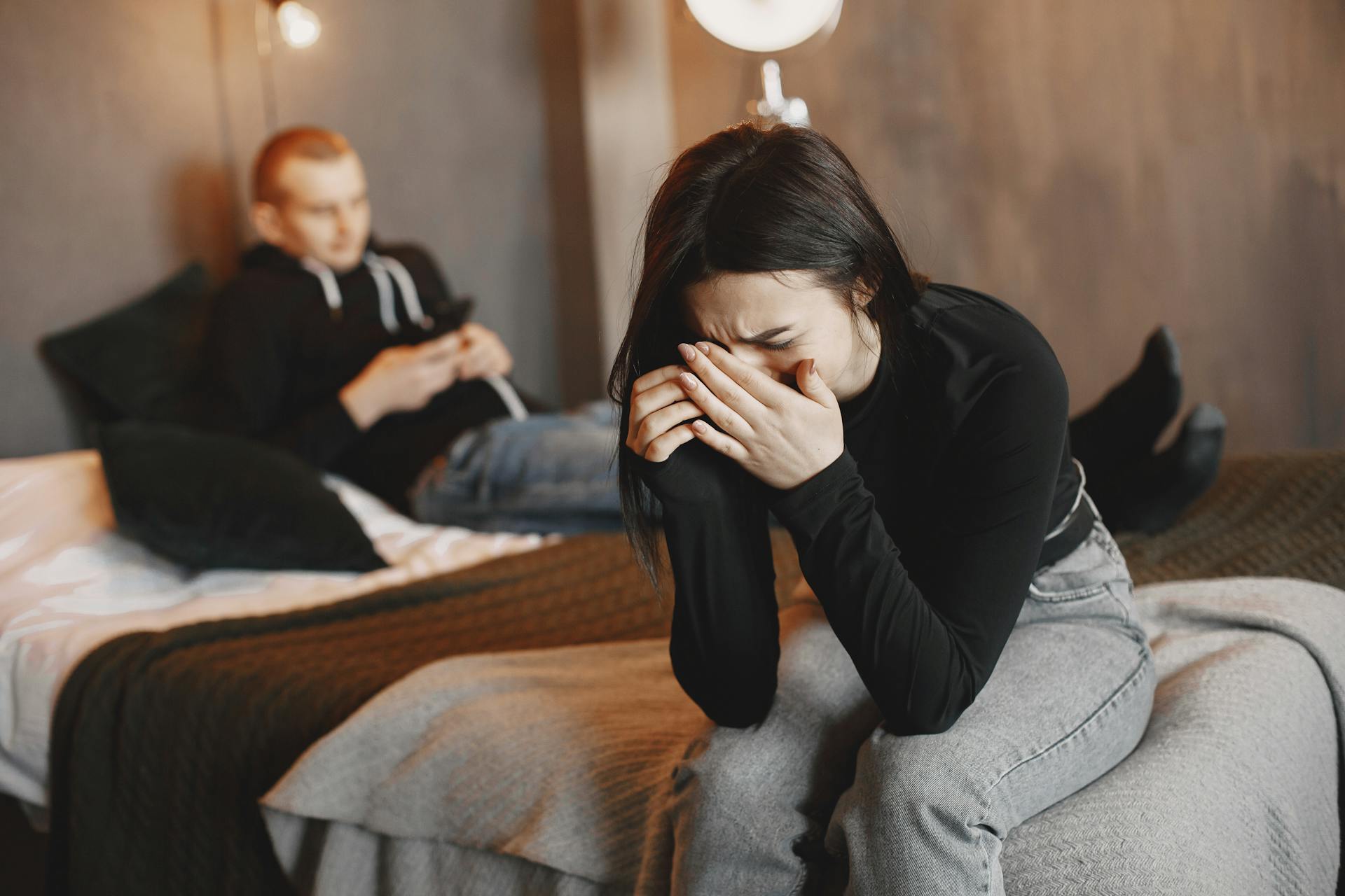 An upset woman sitting on the bed with a man | Source: Pexels