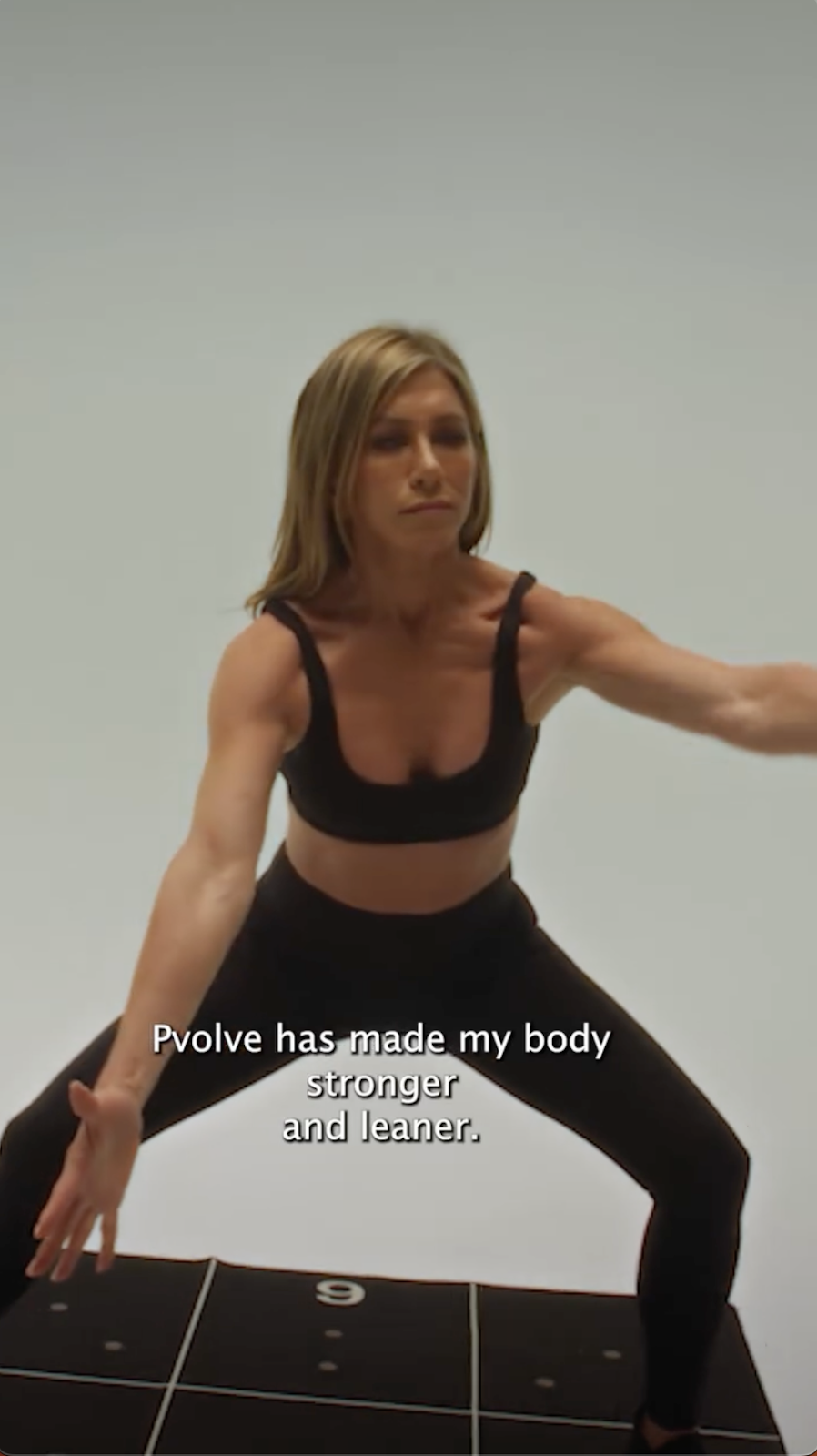 Jennifer Aniston performs a squat-like movement, engaging her core and lower body as part of a Pvolve workout | Source: Instagram/pvolve