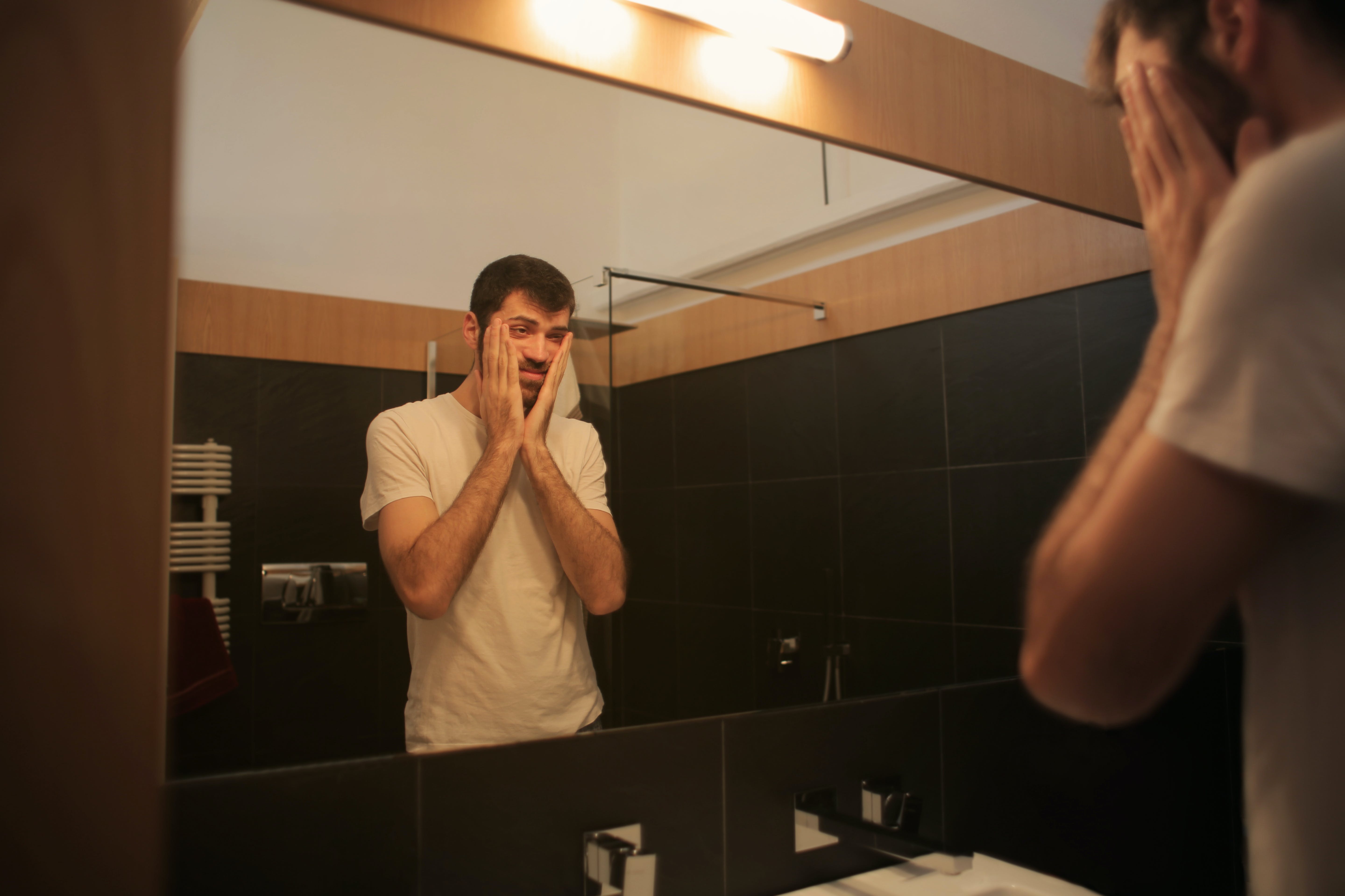 A man in the bathroom looking in the mirror┃Source: Pexels