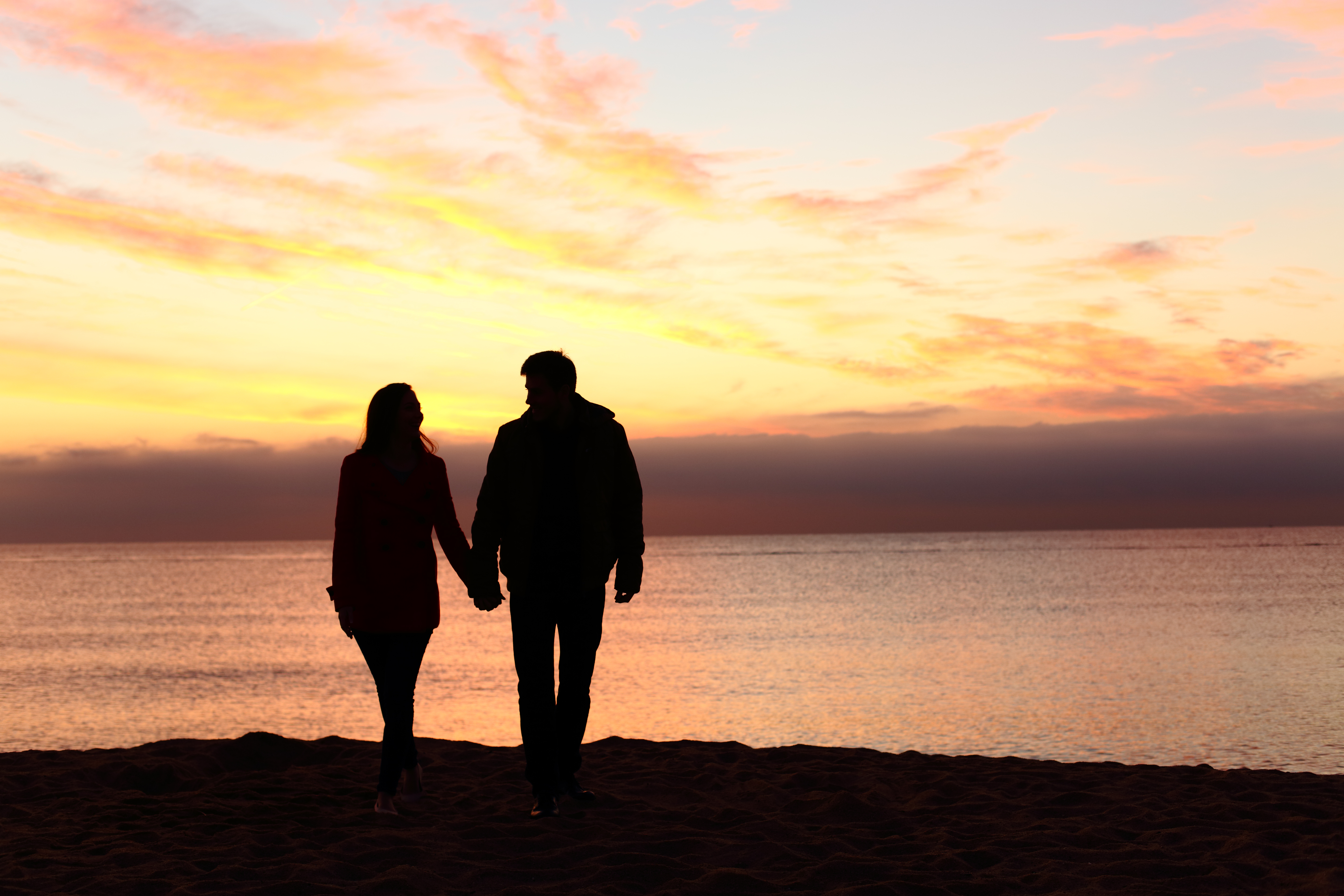 A silhouette of a couple watching the sunset on a beach | Source: Shutterstock