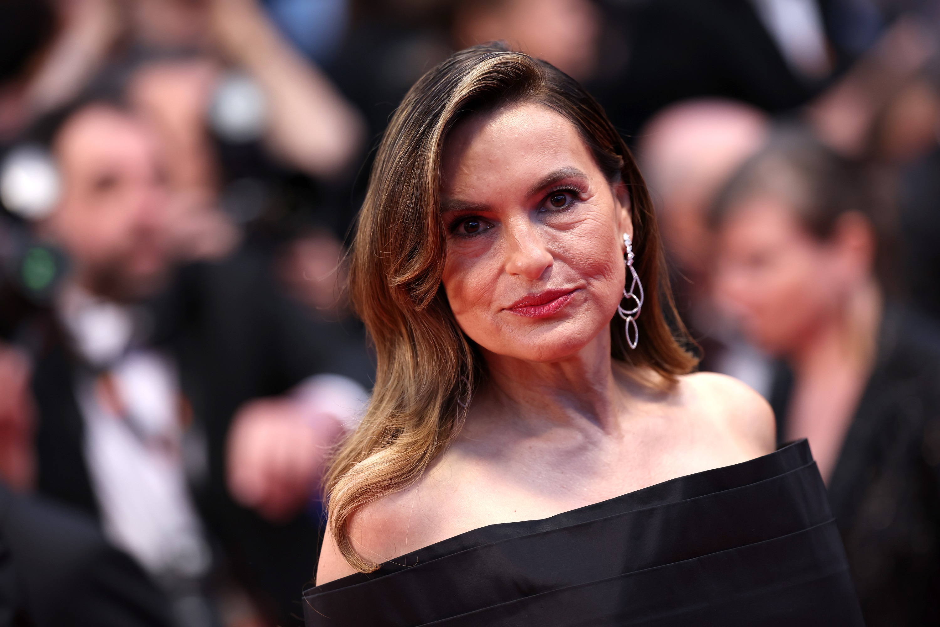 Mariska gazes directly into the camera with quiet intensity, her expression poised and self-assured. The elegance of her look is accentuated by her soft waves and delicate drop earrings, capturing a moment of calm confidence amid the red carpet frenzy.