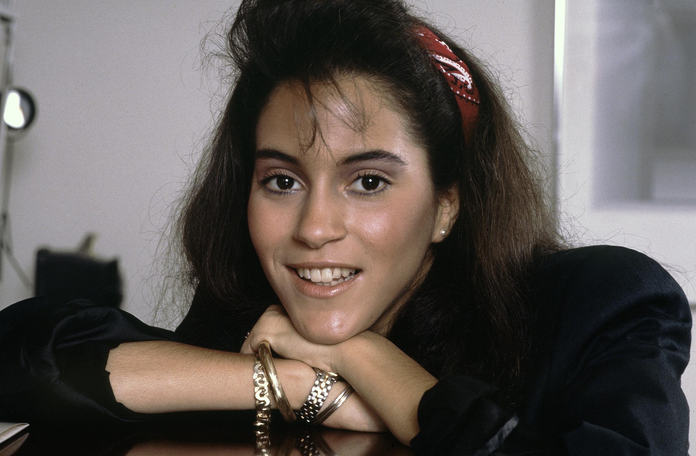 During a Los Angeles portrait session, Jami Gertz leaned forward in a black top and red headband, her sparkling eyes framed by tousled hair.