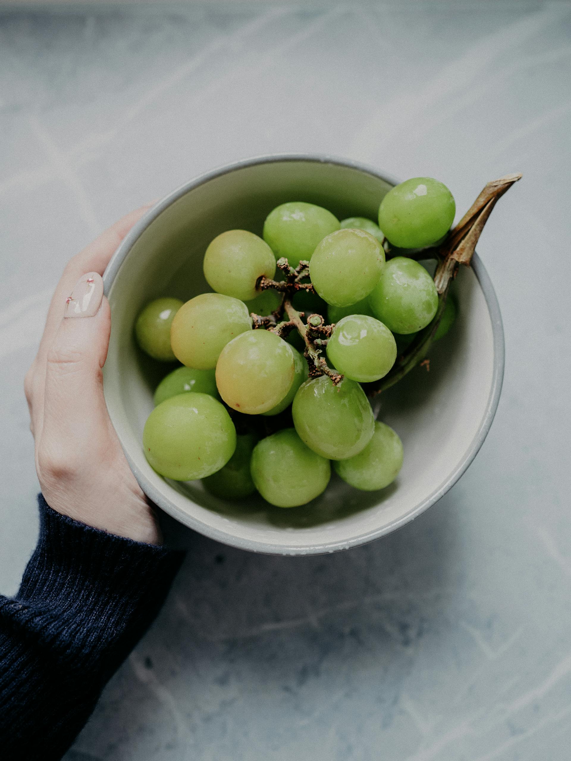 A person holding a bowl of grapes | Source: Pexels