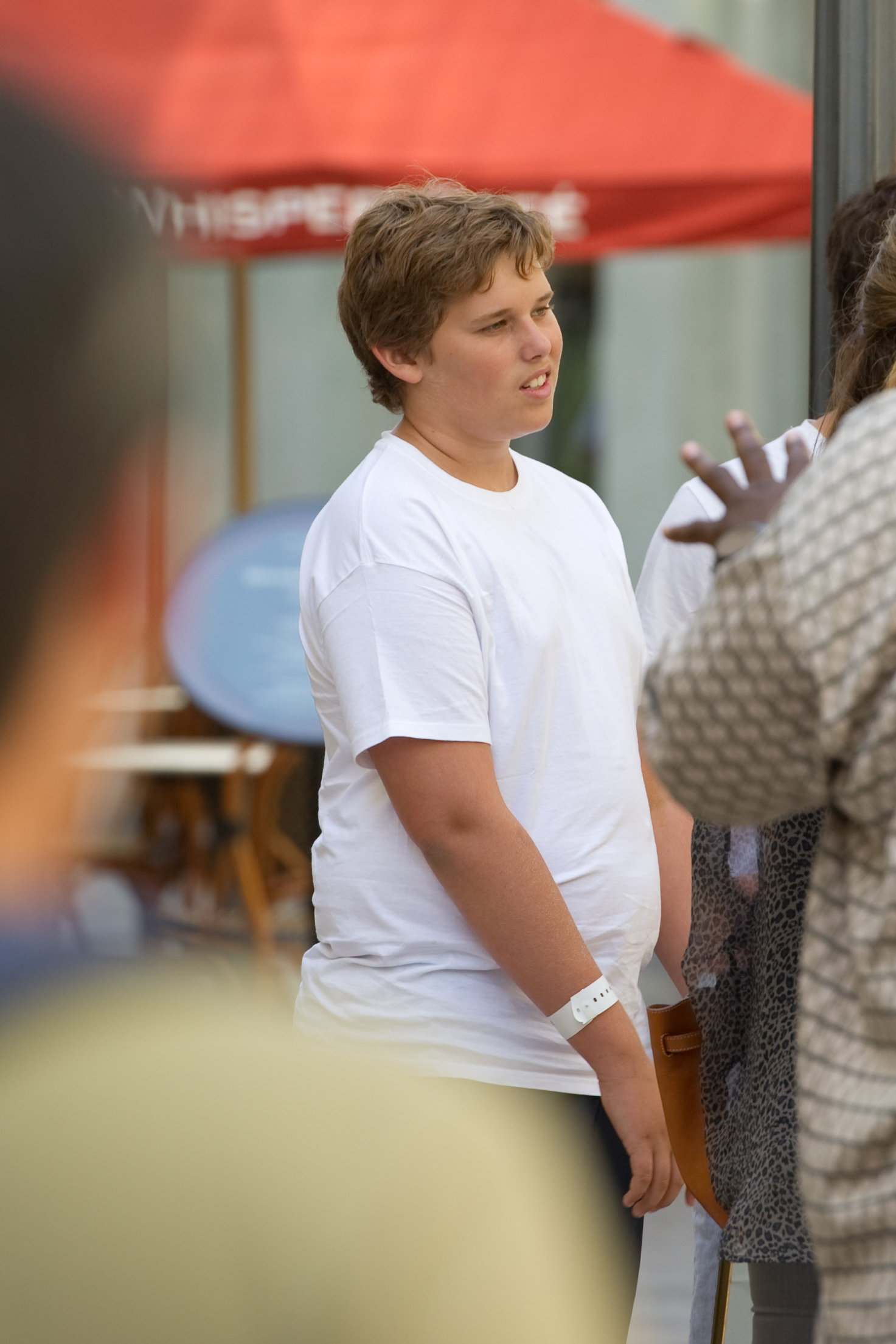 Also taken at The Grove on the same day, this photo captures Christopher listening intently during a conversation. His youthful face and short, tousled hair frame his expression, while a white wristband is visible on his left wrist.