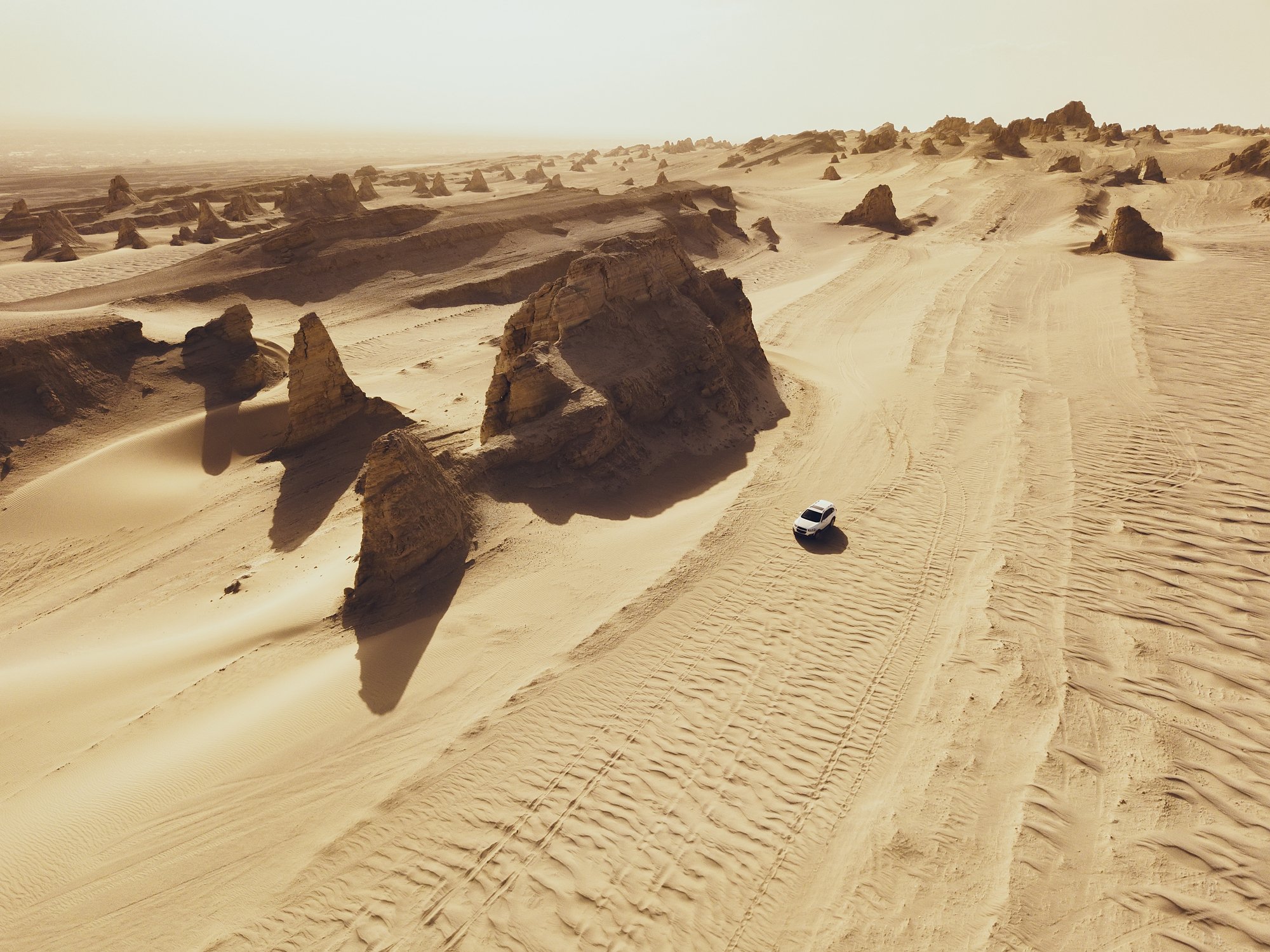 Aerial view of white car on desert road  | Photo: Getty Images