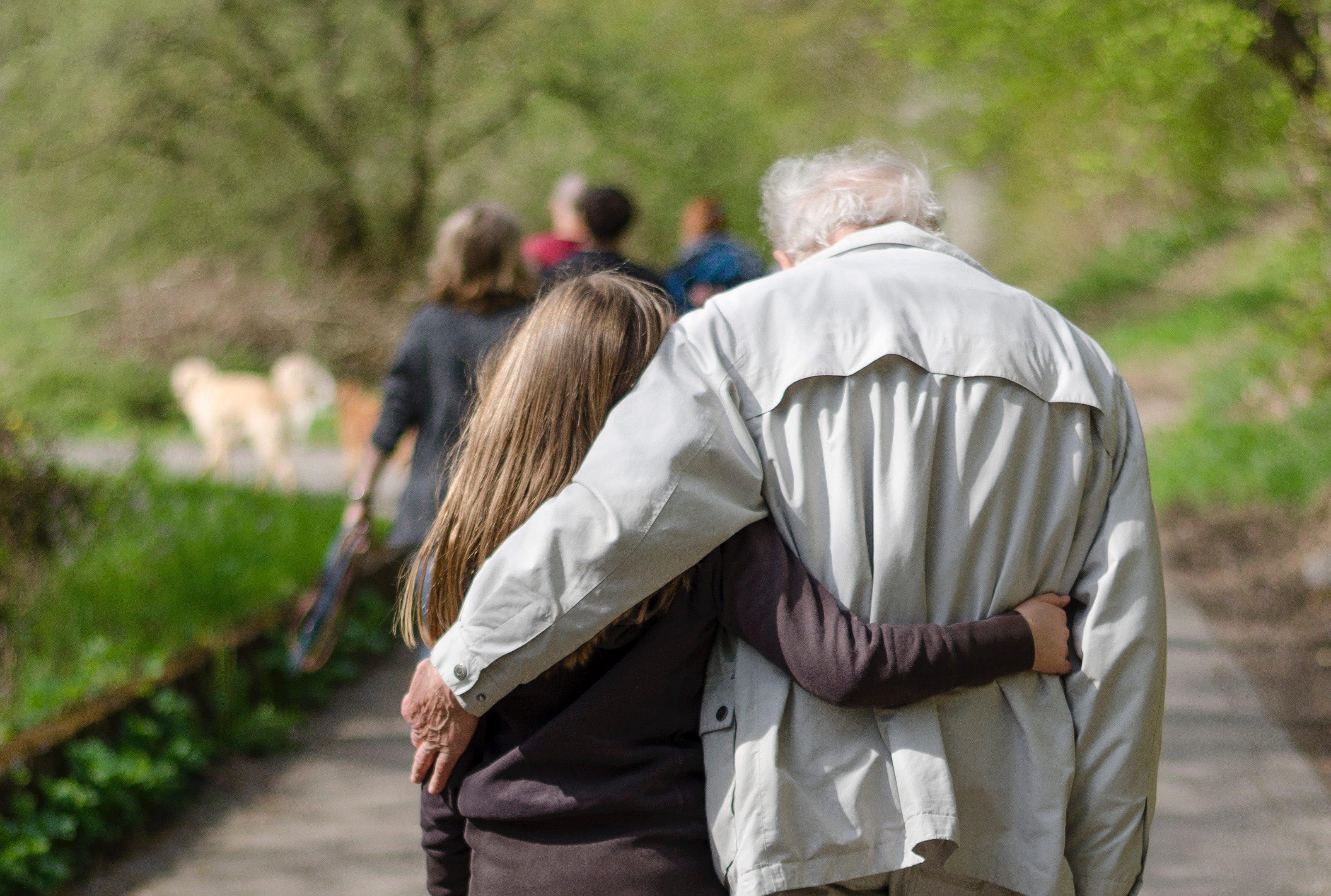 Un anciano y una mujer joven caminan abrazados. | Foto: Unsplash