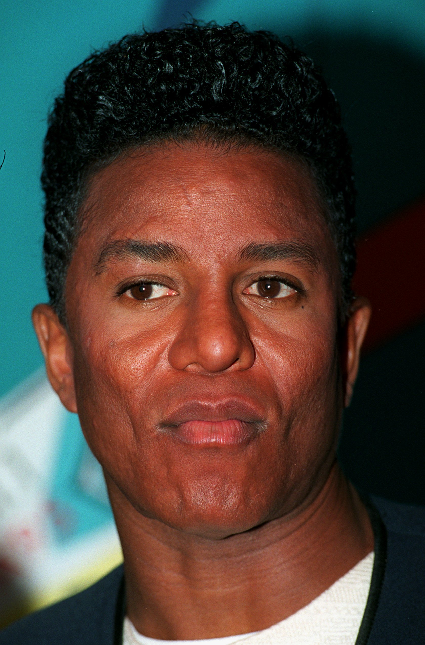 Jermaine Jackson appears in a close-up portrait in Berlin, his neatly styled hair and calm gaze reflecting a polished mid-1990s image. The minimal styling and direct expression place full focus on his features, capturing a quiet, composed confidence.