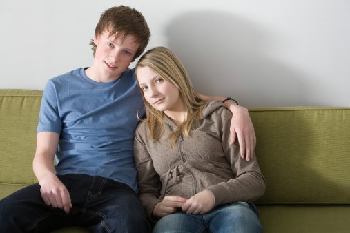 Portrait of a young couple sitting on a sofa | Photo: Getty Images