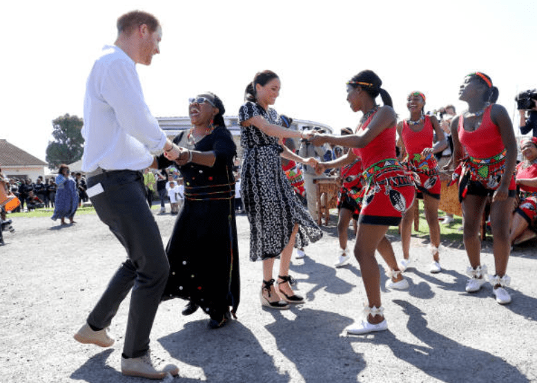 Lors de leur tournée en Afrique, Prince Harry et Meghan Markle dansent avec les habitants lors d'une visite organisée à l'initiative de la justice dans la banlieue de Nyanga, le 23 septembre 2019 à Cape Town, en Afrique du Sud. | Source: Getty Images