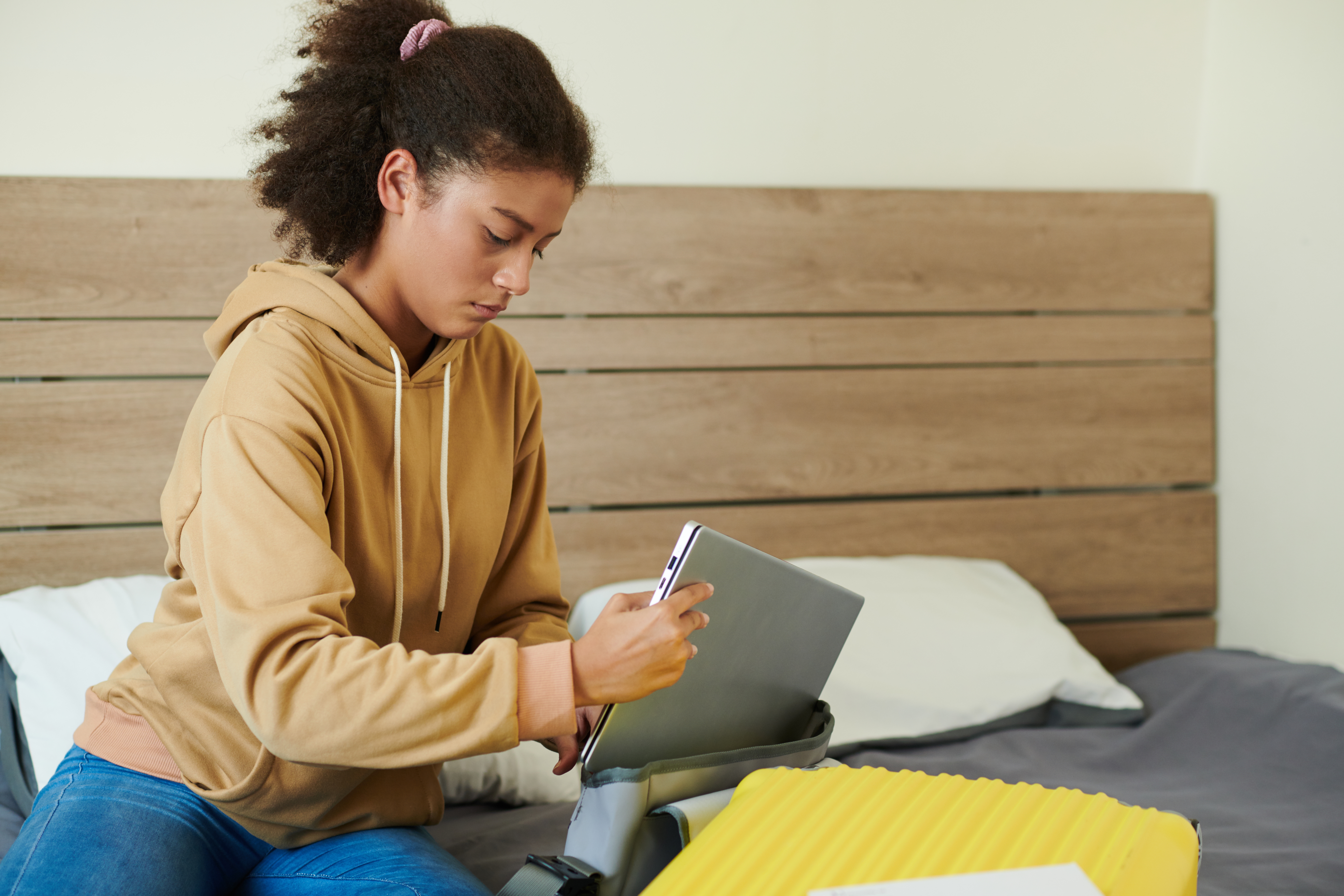 Serious teenage girl putting laptop in bag when packing to leave for university | Source: Shutterstock.com