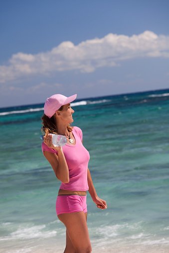 Une femme en short et tee-shirt rose à la plage. | Photo : Getty Images