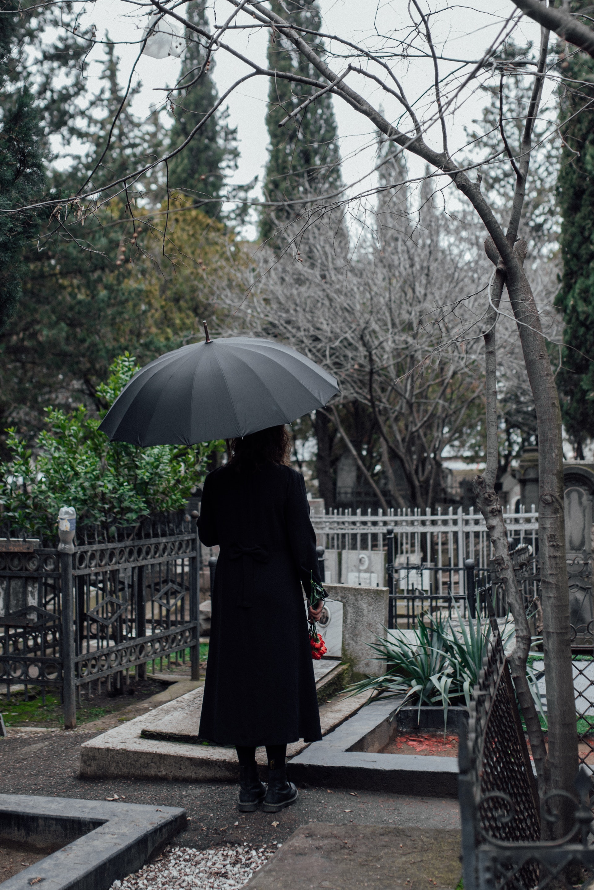 A woman holding an umbrella at the cemetery | Source: Pexels