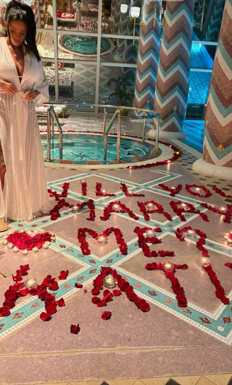 Laid out beside the pool like something out of a fairytale fever dream, rose petals and glowing candles spelled out the proposal that left Price stunned: "Will you marry me Katie?" | Source: Instagram/katieprice