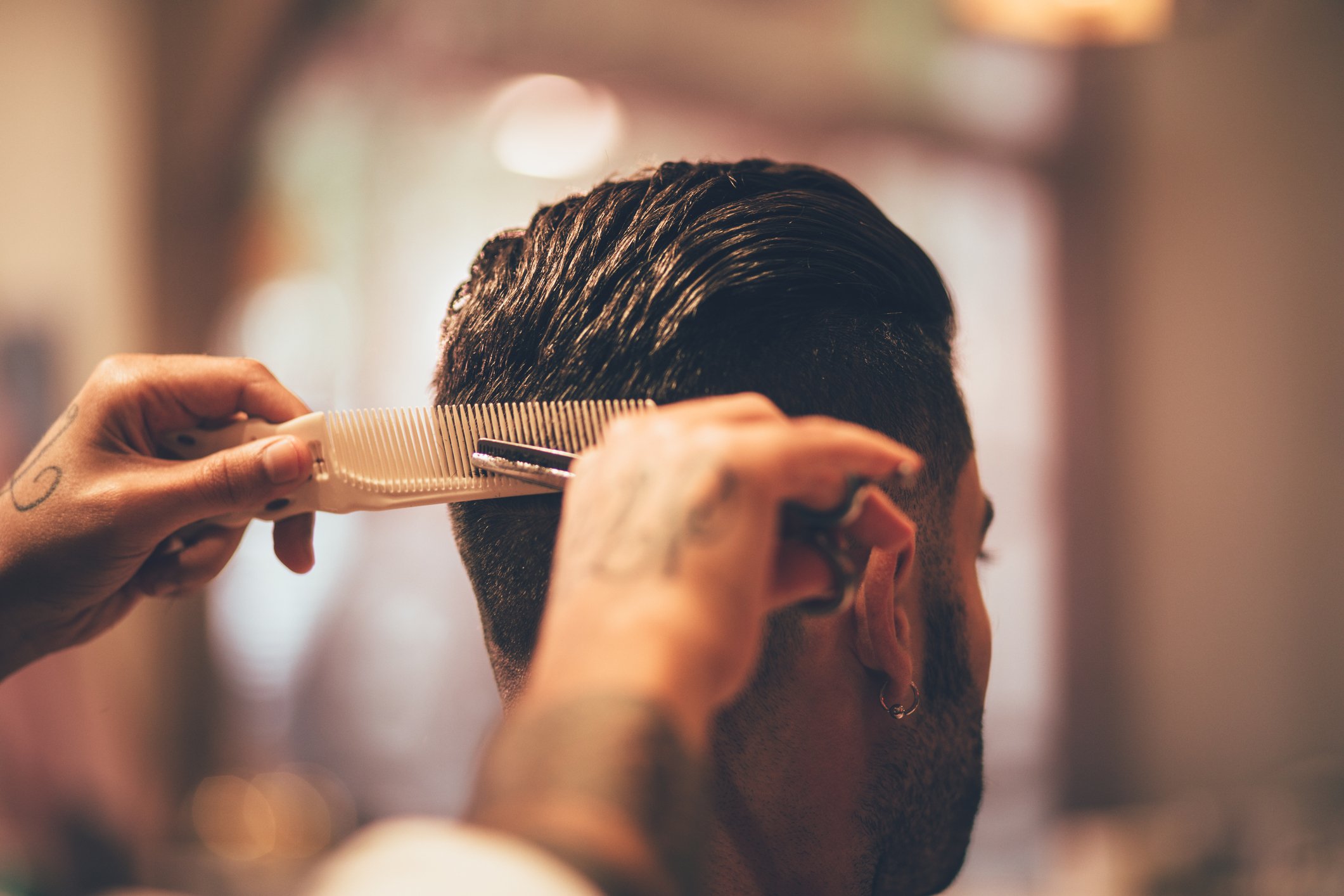 A close-up photo of a hairstylist cutting a man's hair. | Photo: Getty Images