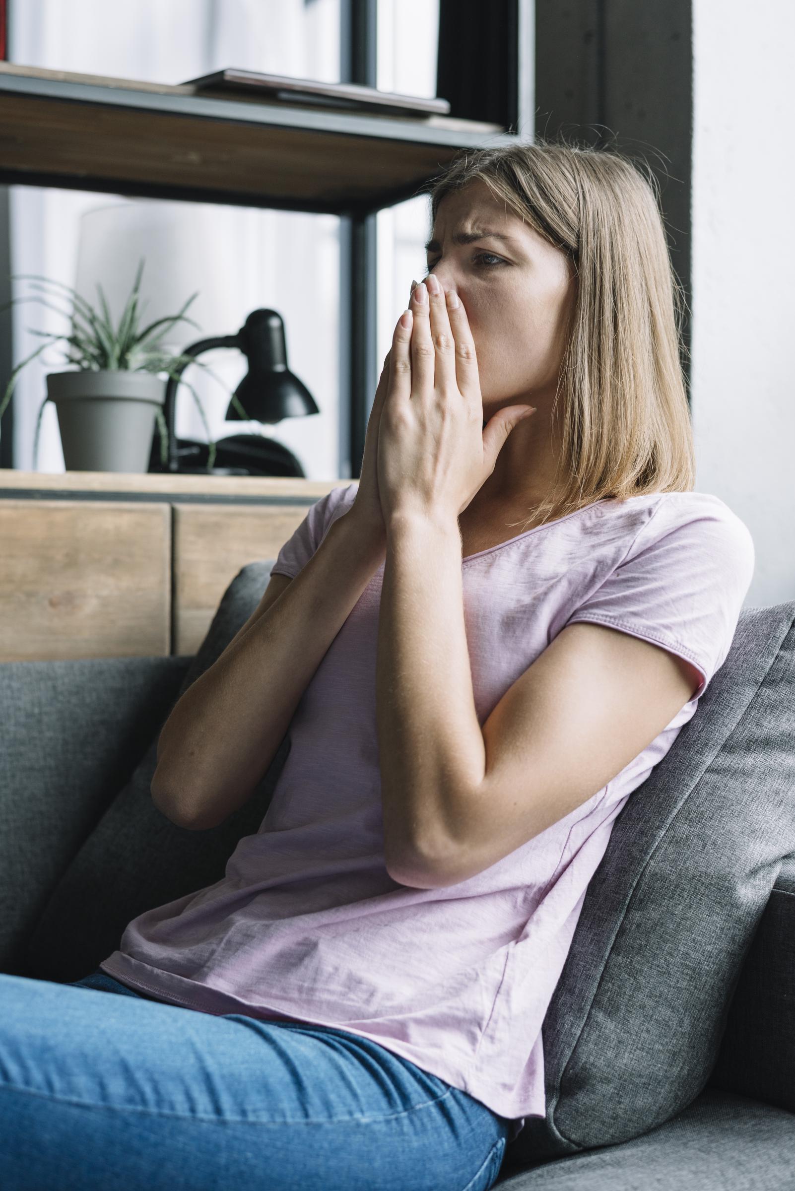 A distressed woman siting on the couch | Source: Freepik