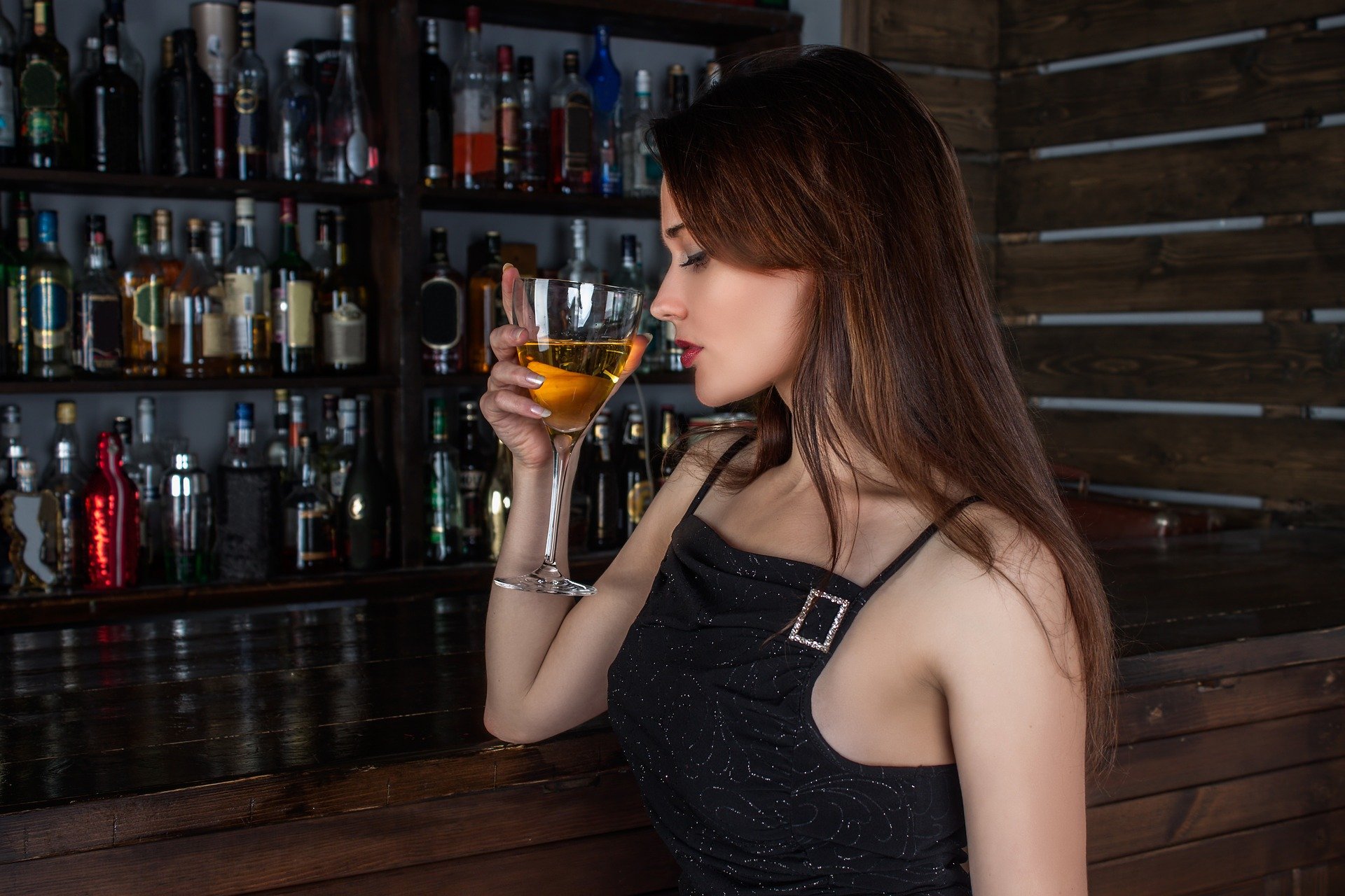 A woman holds a cocktail glass while at the bar counter | Source: Pixabay