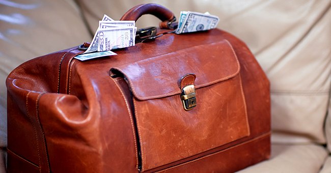 Money coming out of a red leather bag. | Source: Shutterstock