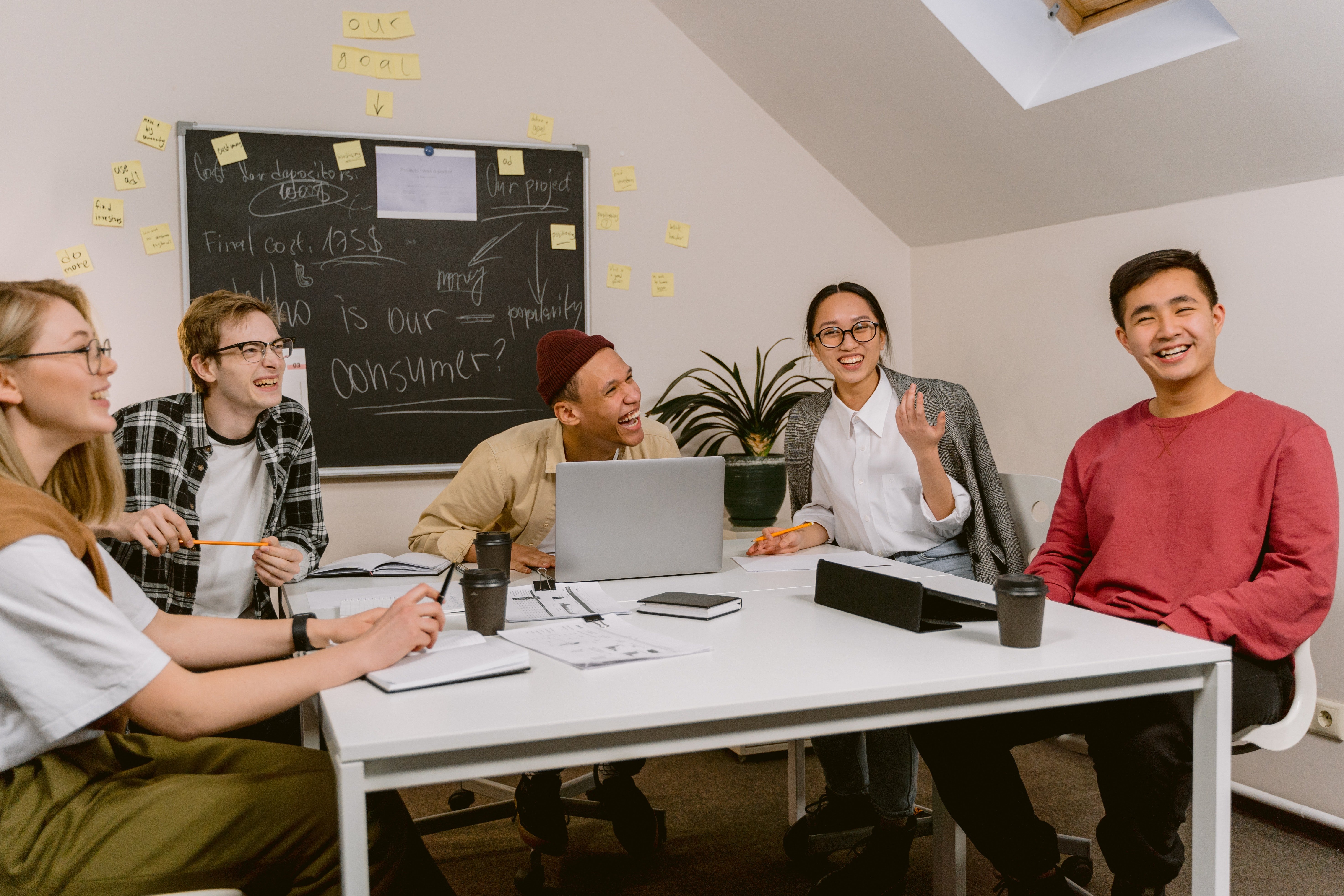 Varias personas sentadas alrededor de una mesa, rien. | Foto: Pexels