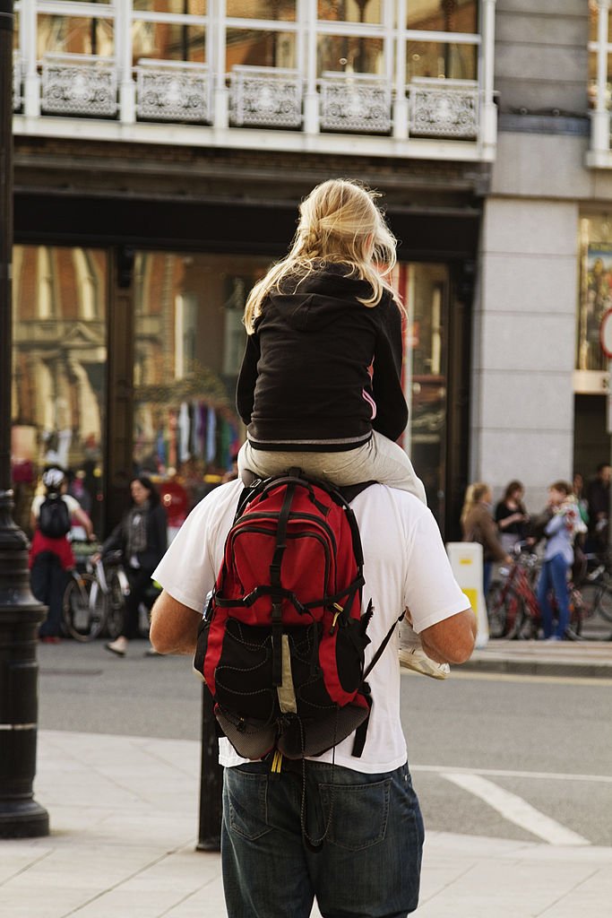 Un homme qui porte sa fillette sur les épaules. | source : Getty Images