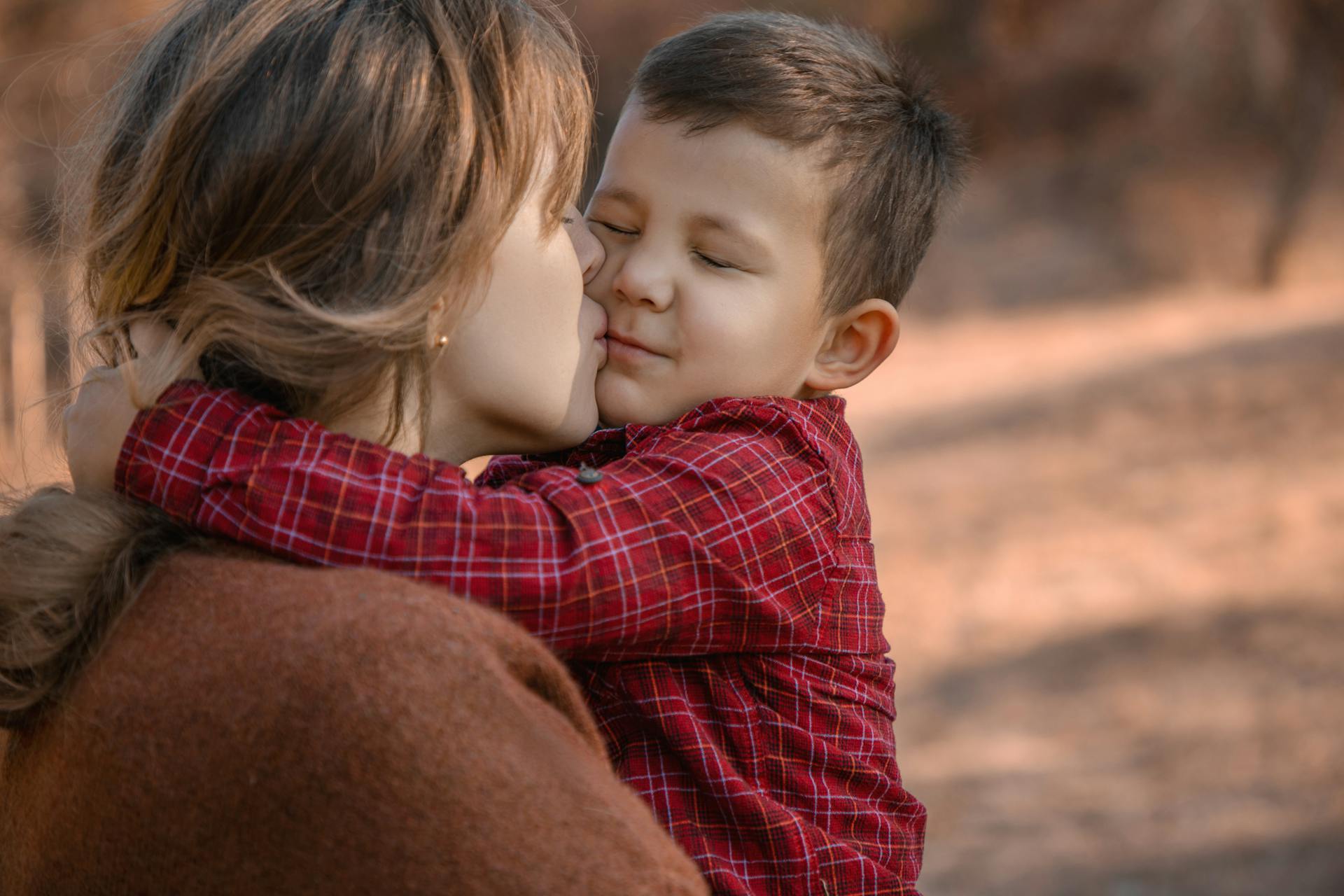 A mother kissing her little boy in a park | Source: Pexels