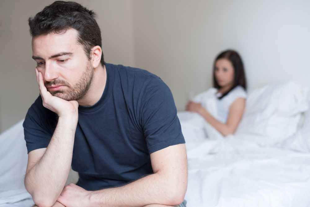 A man looks into space while his wife sits behind. | Source: Shutterstock